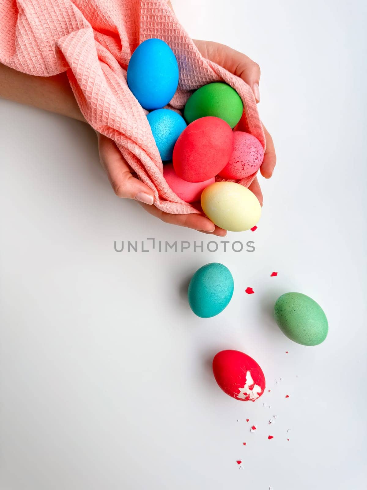 Hands holding colorful painted Easter eggs with one cracked egg on the side, representing Easter festivities, spring celebrations, and family fun activities. by Lunnica