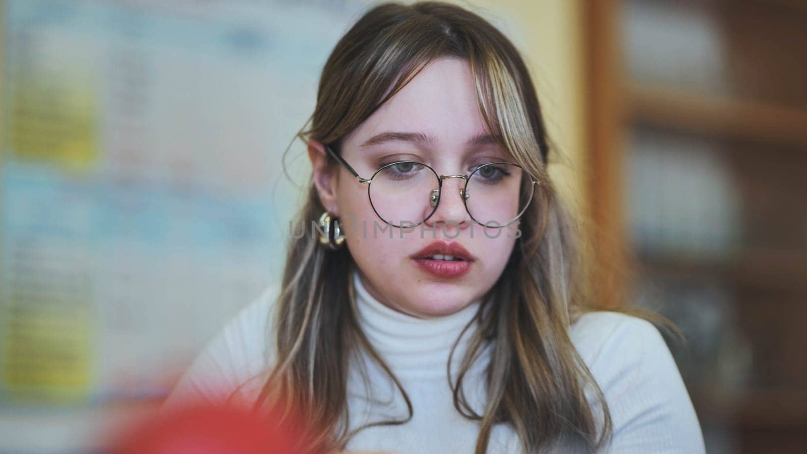 Schoolgirl with glasses at her desk at school. by DovidPro