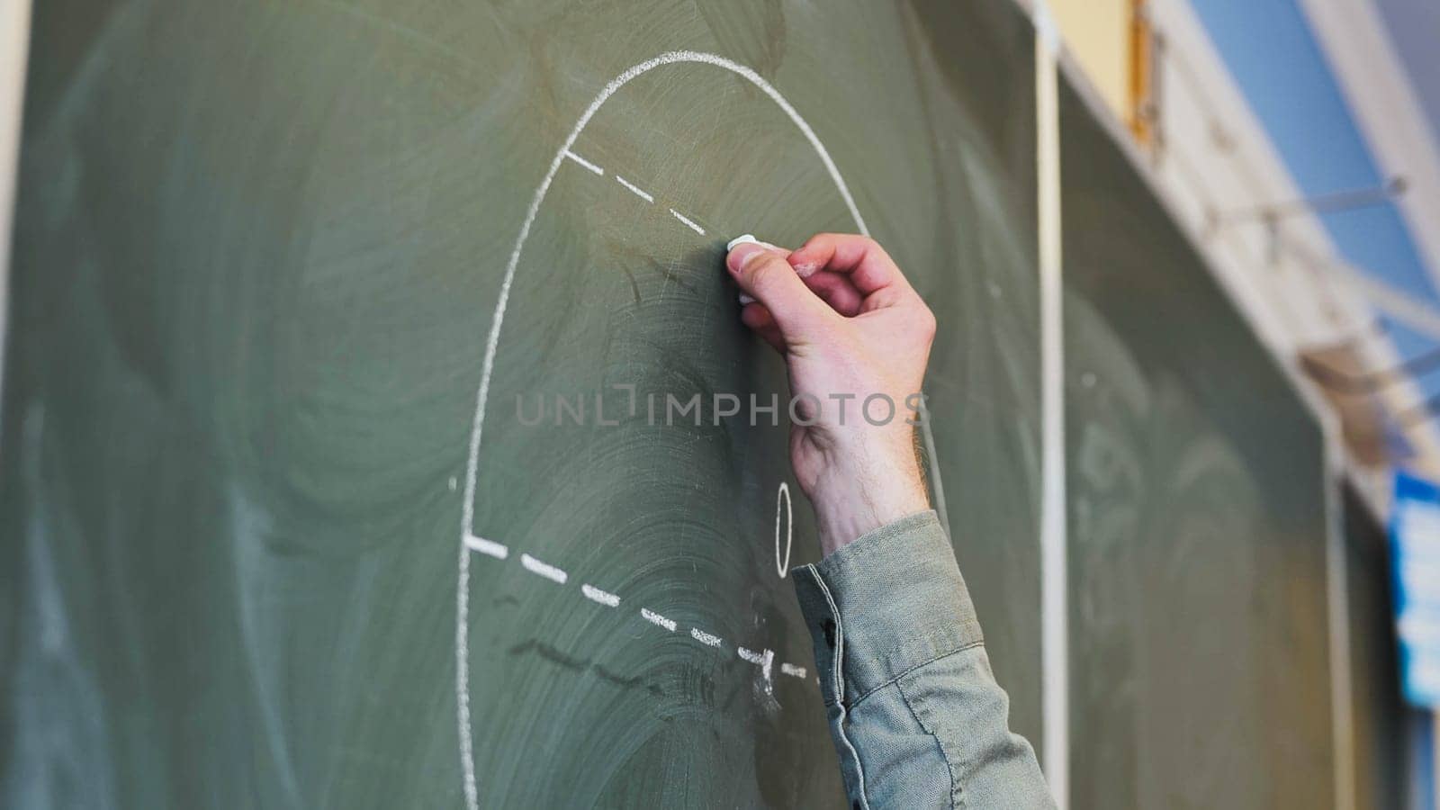 Guy draws figures on the board. Geometry class