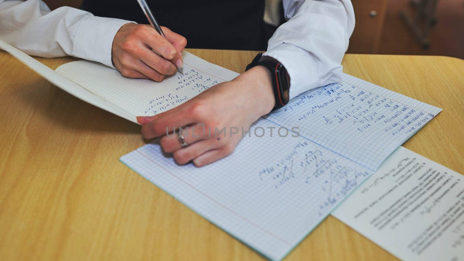 A girl student writes math formulas in a notebook. Notebook close-up. by DovidPro