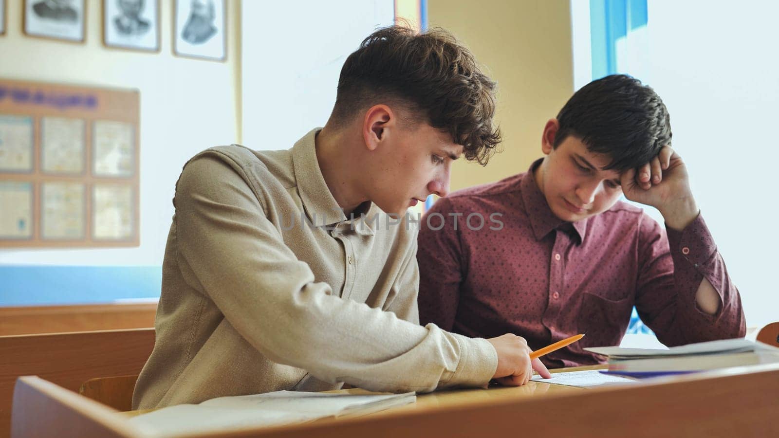 Schoolboys at a desk during class. by DovidPro