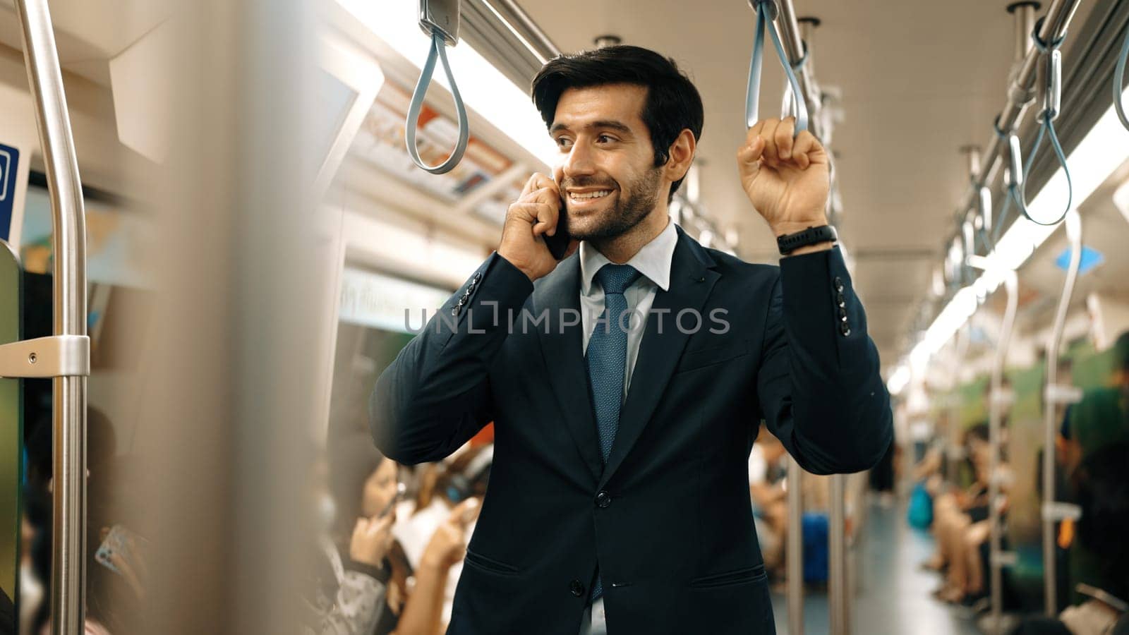 Smart business man phone calling to project manager while standing in train. Professional male leader talking to investor about marketing plan by using phone with blurring background. Exultant.