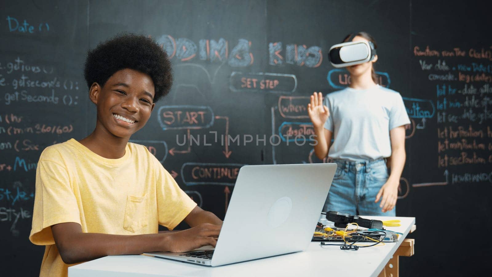 Smart african student programing and coding innovative system while caucasian girl enter in metaverse or virtual world by using VR or head set at blackboard in STEM technology classroom. Edification.