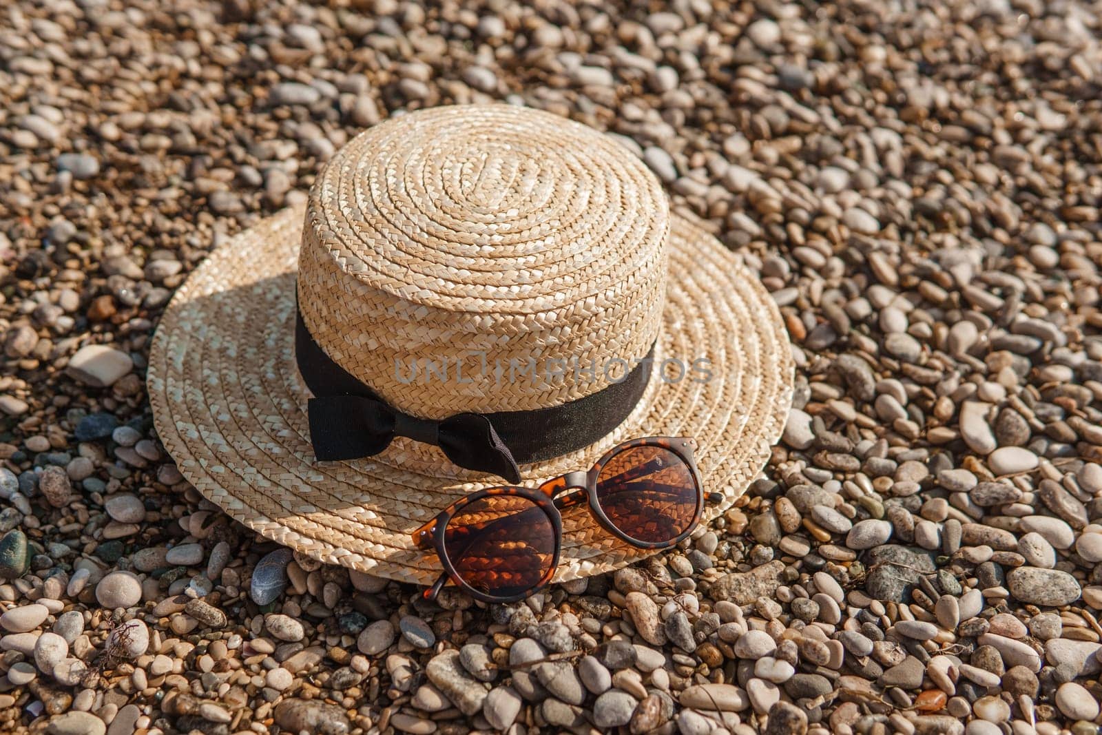 A straw hat and sunglasses on the beach. Pebbles on the seashore, close-up. The natural background. by Annu1tochka