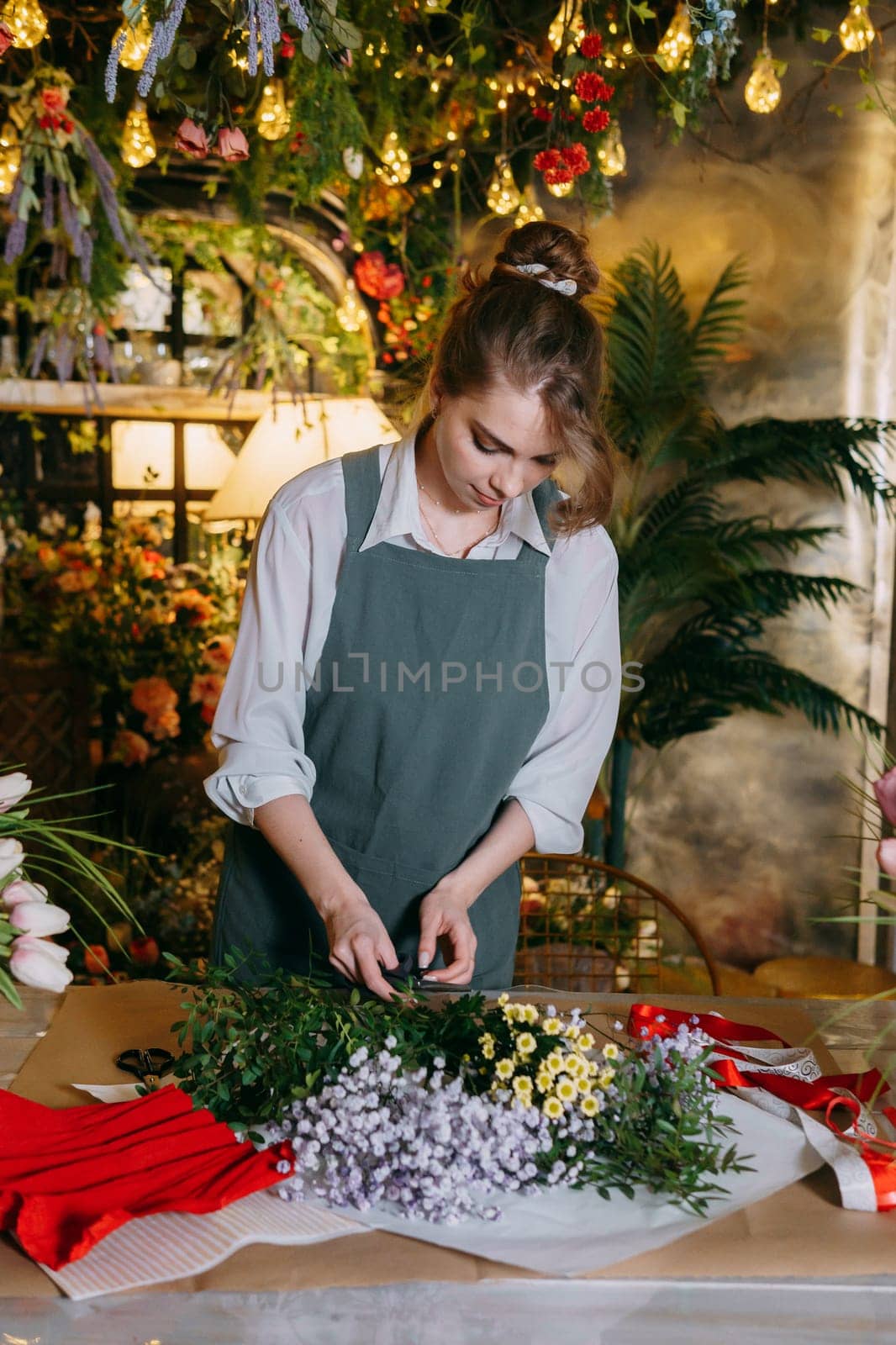 A woman in her florist shop collects bouquets of flowers. The concept of a small business. Bouquets of tulips for the holiday on March 8