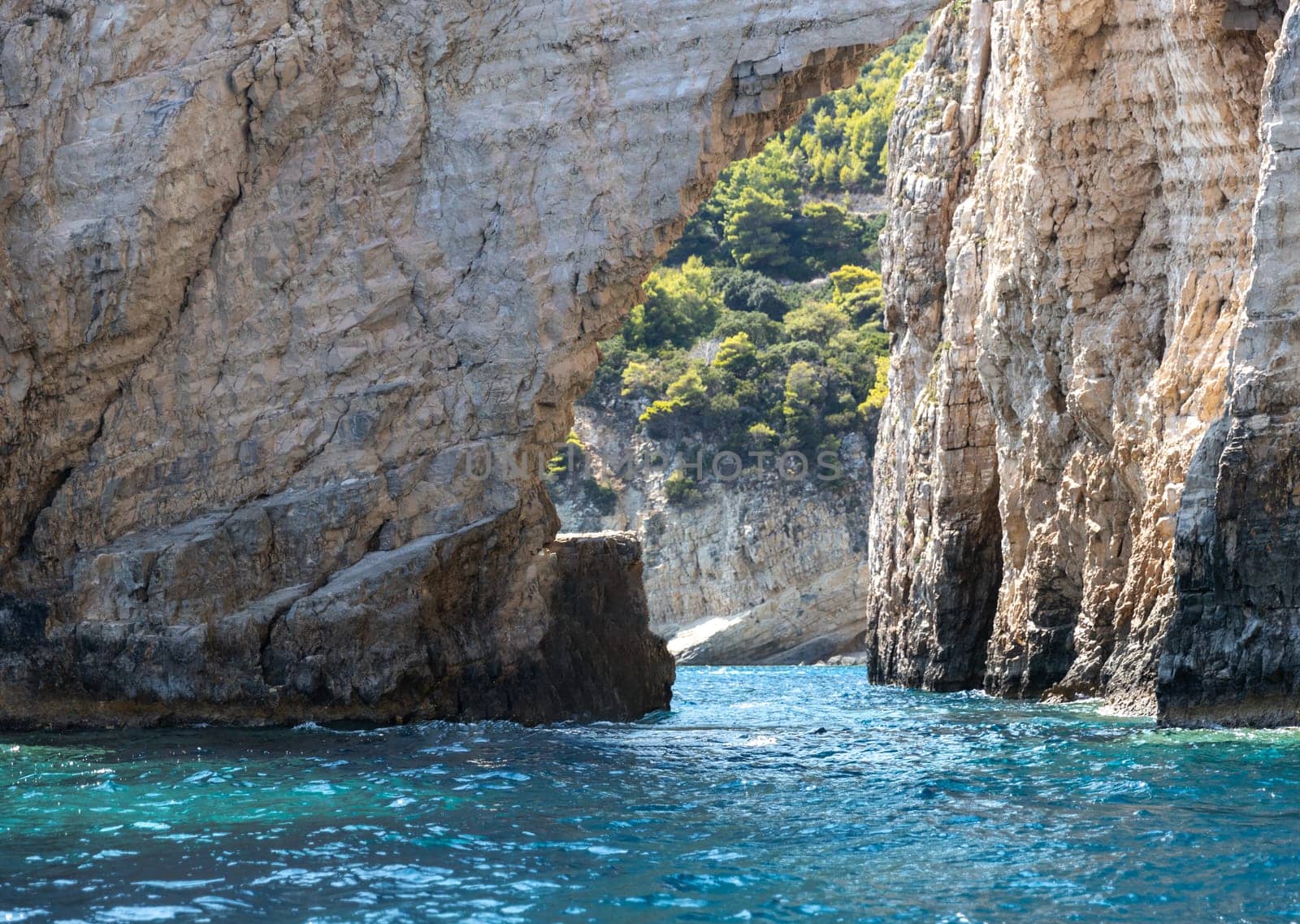 Beautiful view of a natural rocky arch in the blue sea on a sunny summer day on zakynthos island, side view close up.