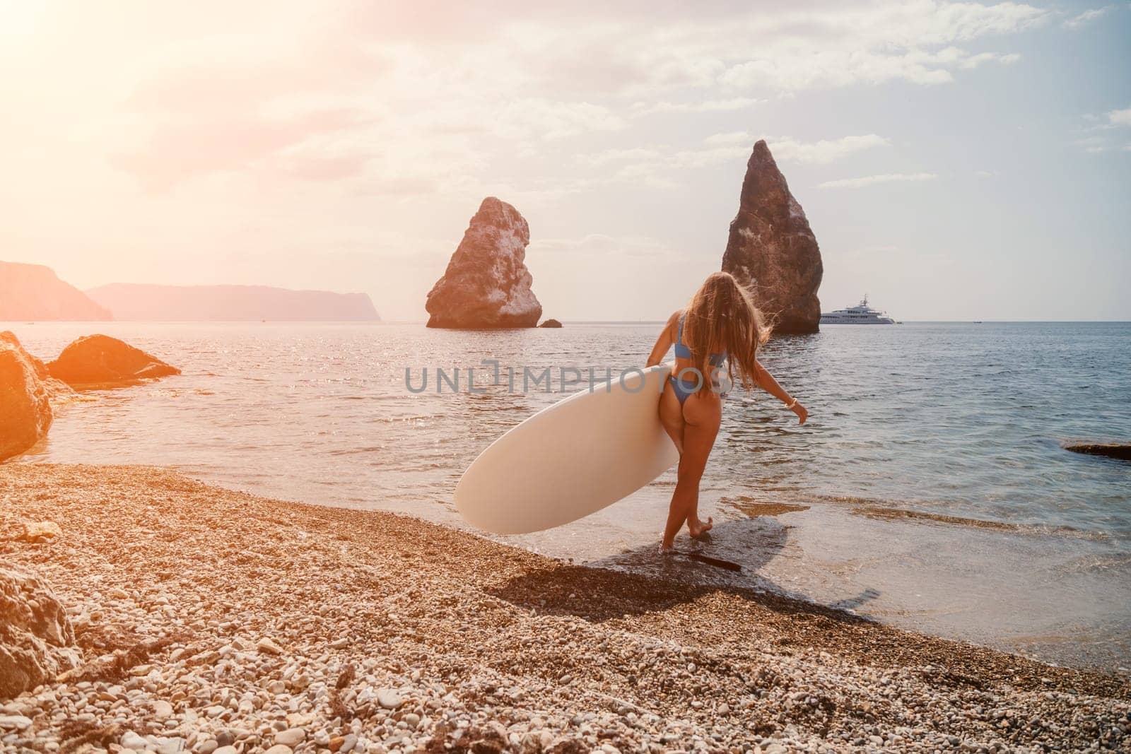 Close up shot of beautiful young caucasian woman with black hair and freckles looking at camera and smiling. Cute woman portrait in a pink bikini posing on a volcanic rock high above the sea