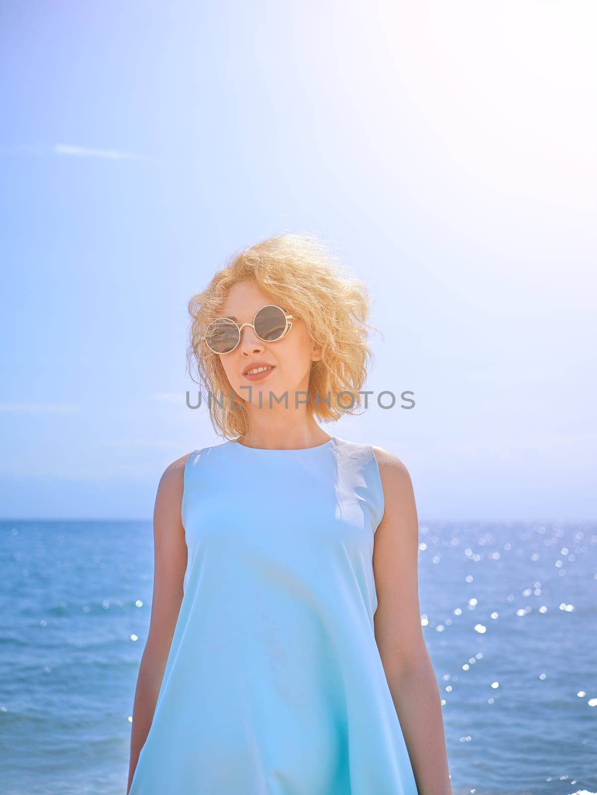 Beautiful blondy woman in cyan dress on the beach
