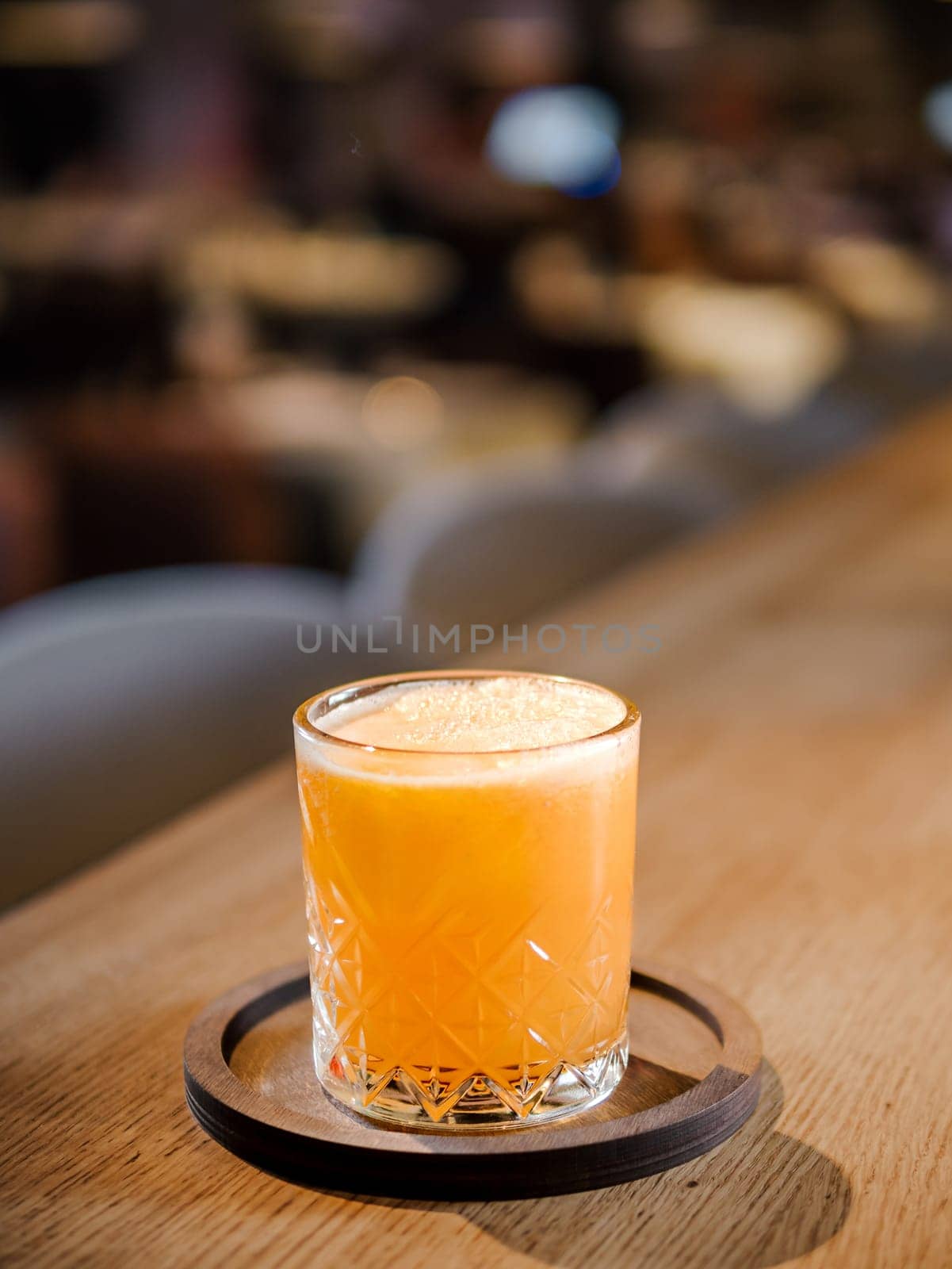 Glass of fresh orange juice on bar counter in restaurant interior. Delicious cold orange fresh juice or cocktail in bar or nightclub. Copy space