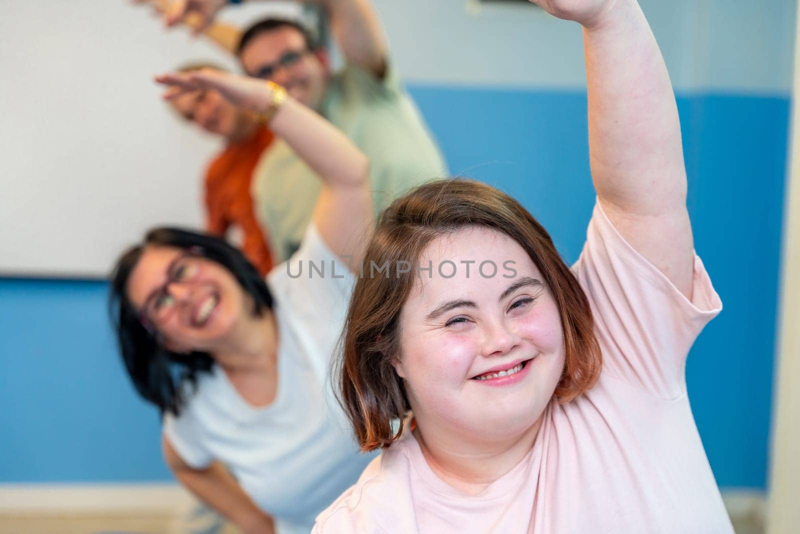 Happy group of people with special needs enjoying gymnastics stretching the back together
