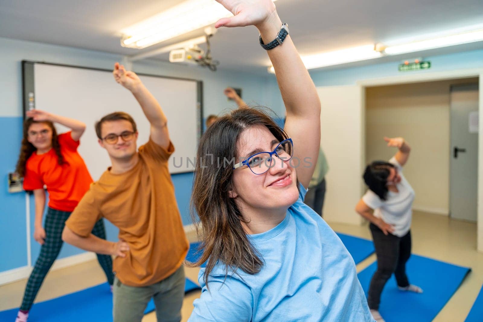Happy people with special needs exercising in a gym by Huizi