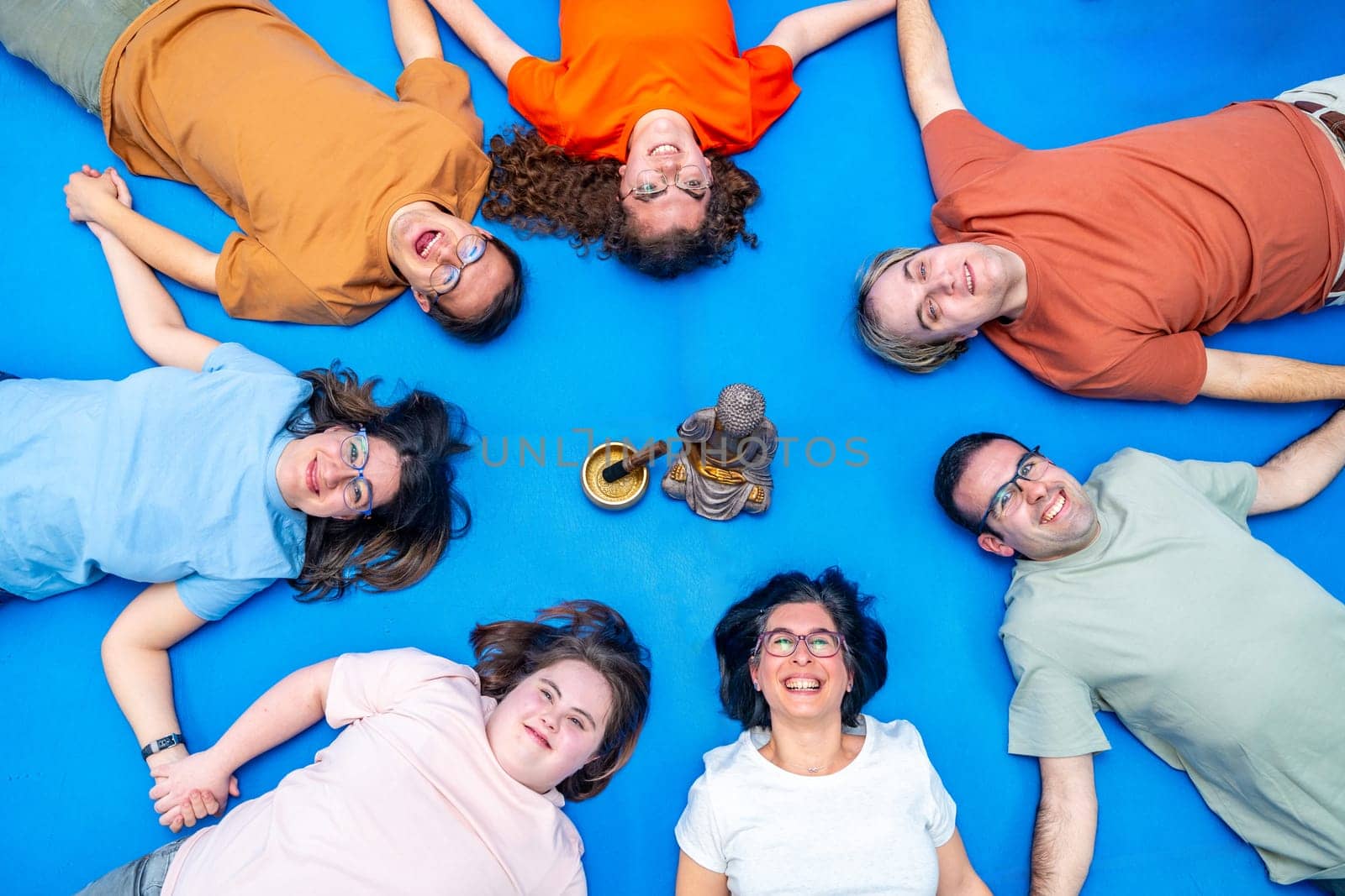 Disabled people lying holding hands and forming a circle in the gym