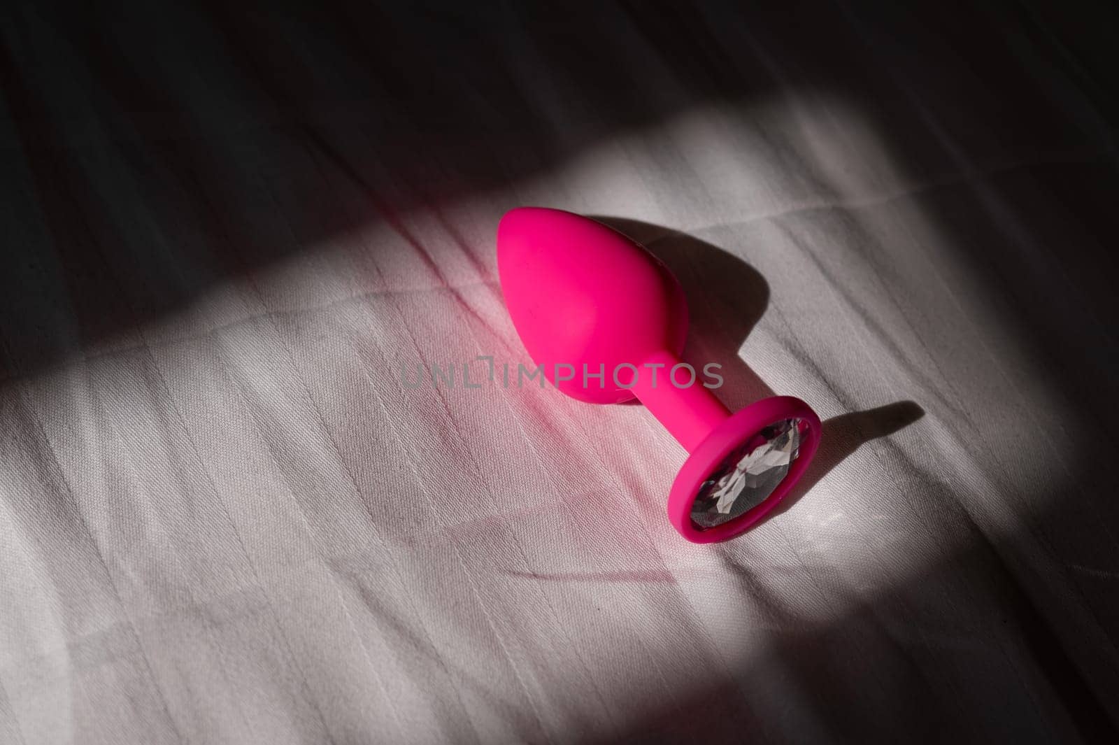 Pink silicone anal plug on a white sheet. by mrwed54