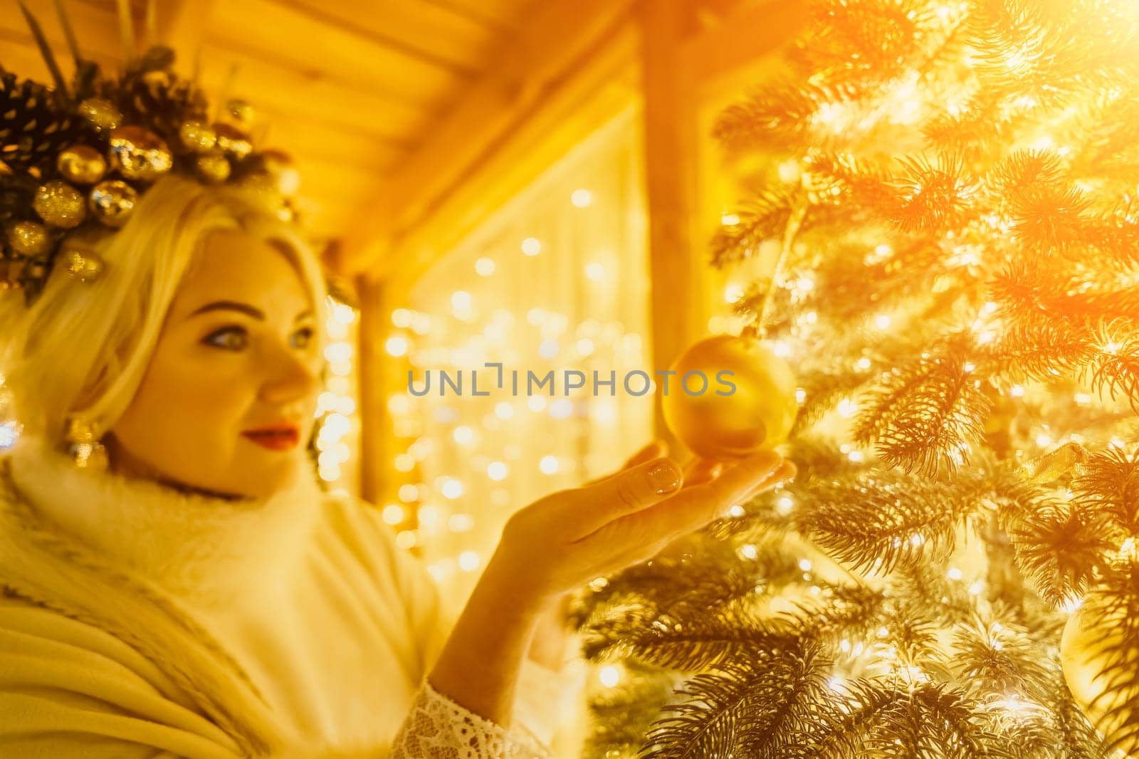 A Christmas tree with gold ornaments and lights. The tree is decorated with gold balls and is lit up with lights.