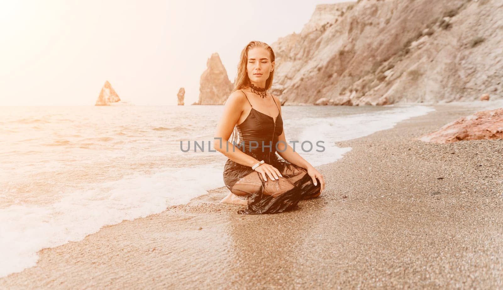 Woman travel sea. Young Happy woman in a long red dress posing on a beach near the sea on background of volcanic rocks, like in Iceland, sharing travel adventure journey