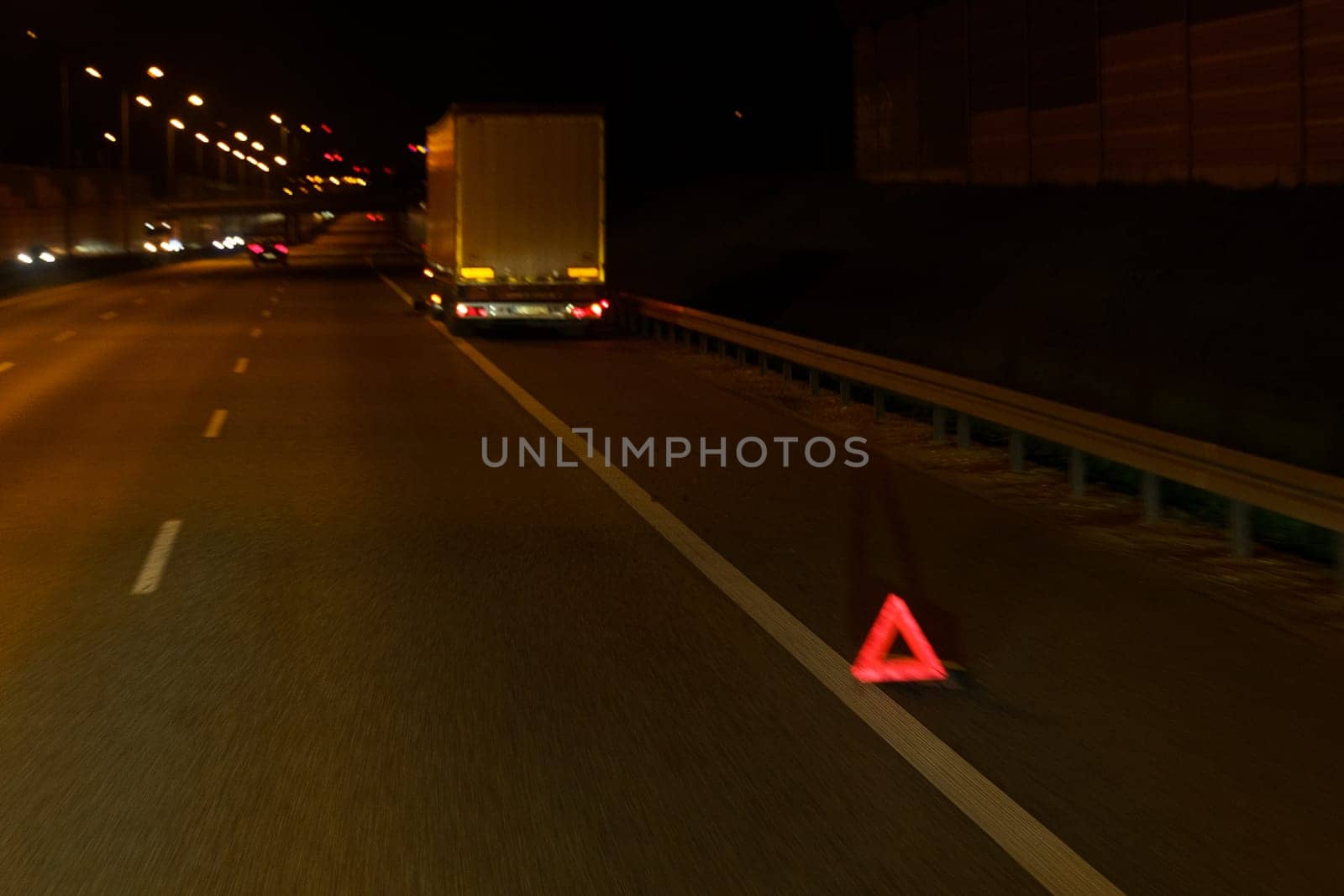 A red triangle sign is placed on the side of a road, alerting drivers to potential hazards or upcoming road conditions.