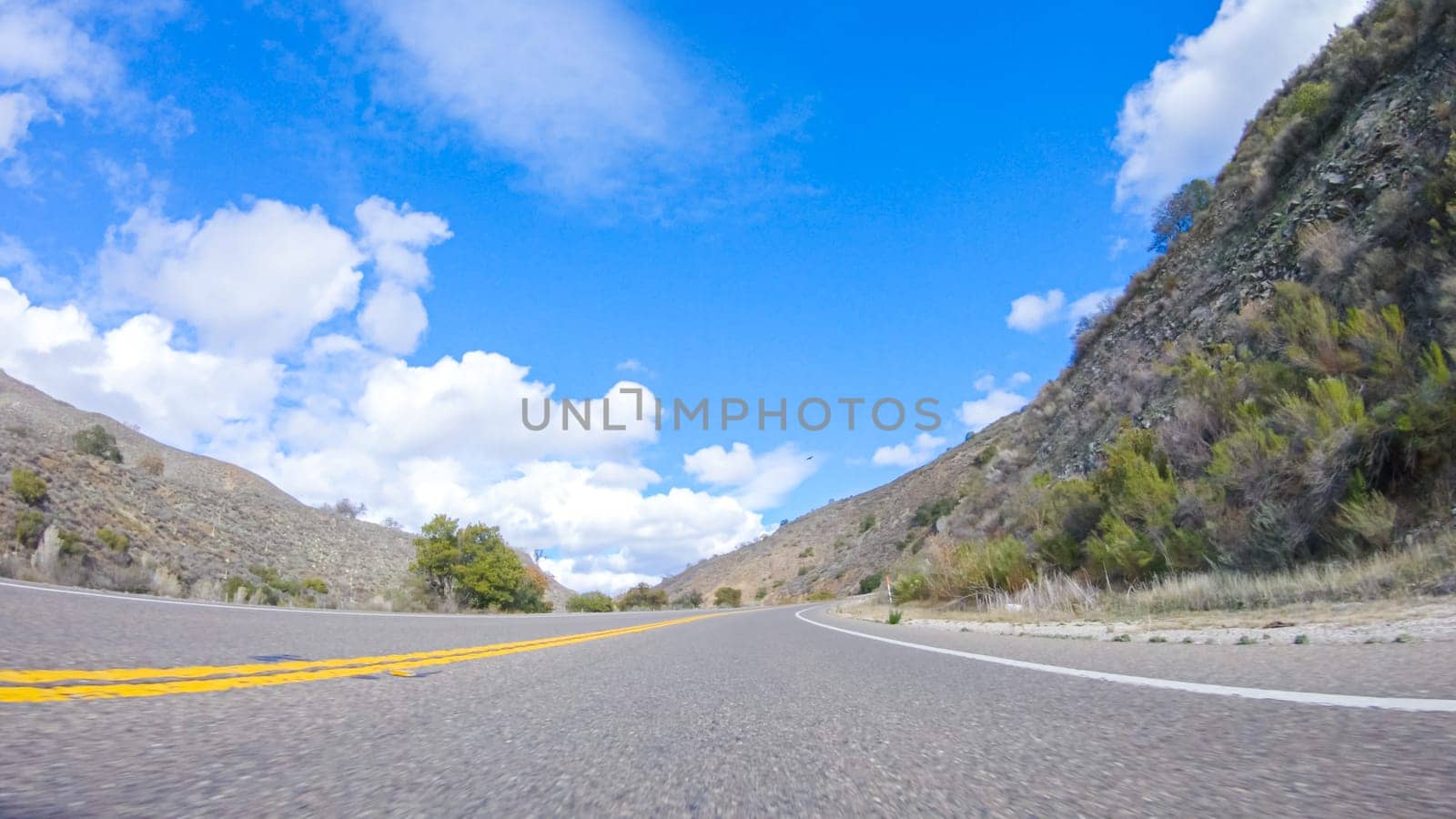 Vehicle is cruising along the Cuyama Highway under the bright sun. The surrounding landscape is illuminated by the radiant sunshine, creating a picturesque and inviting scene as the car travels through this captivating area.