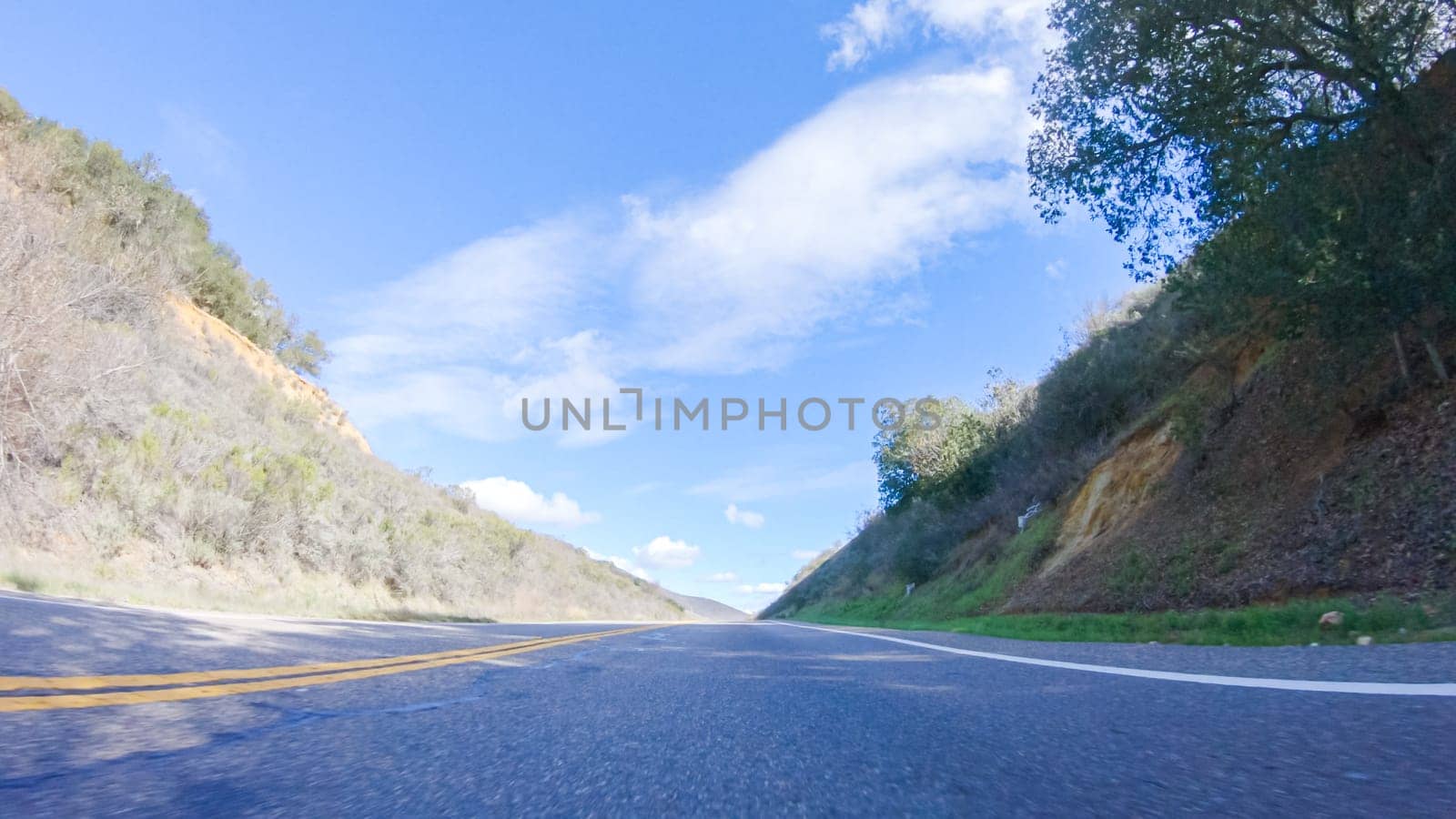 Vehicle is cruising along the Cuyama Highway under the bright sun. The surrounding landscape is illuminated by the radiant sunshine, creating a picturesque and inviting scene as the car travels through this captivating area.