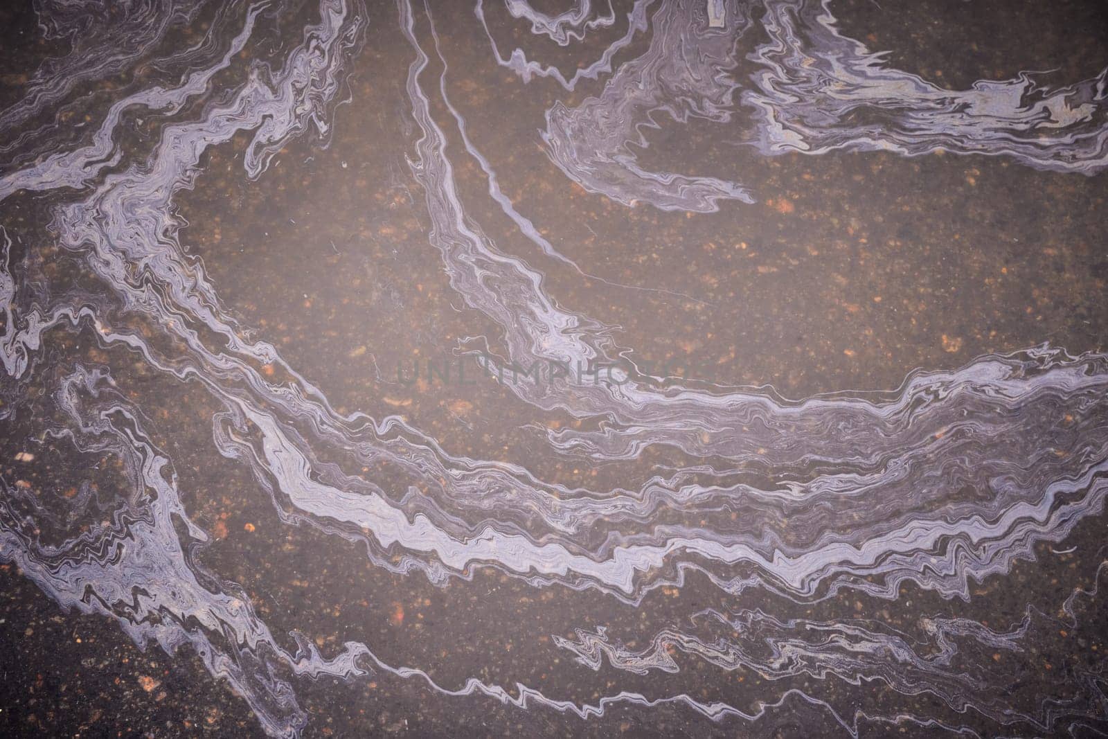 Marble spills on the water from stains of gasoline and oil. Abstract background from motor oil, gas or petrol spilled on asphalt.