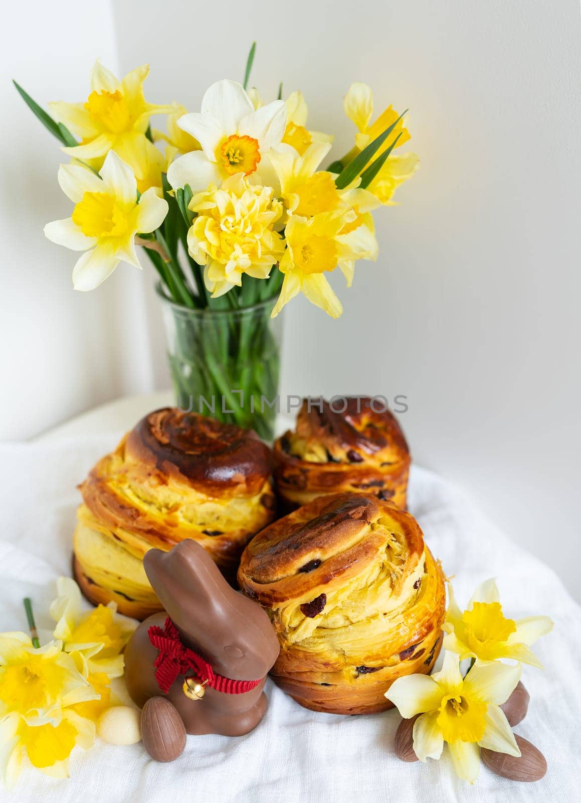 This vibrant image captures a delightful scene of Easter treats and spring vibes. Freshly baked pastries, a chocolate bunny, and colorful daffodils create a festive atmosphere