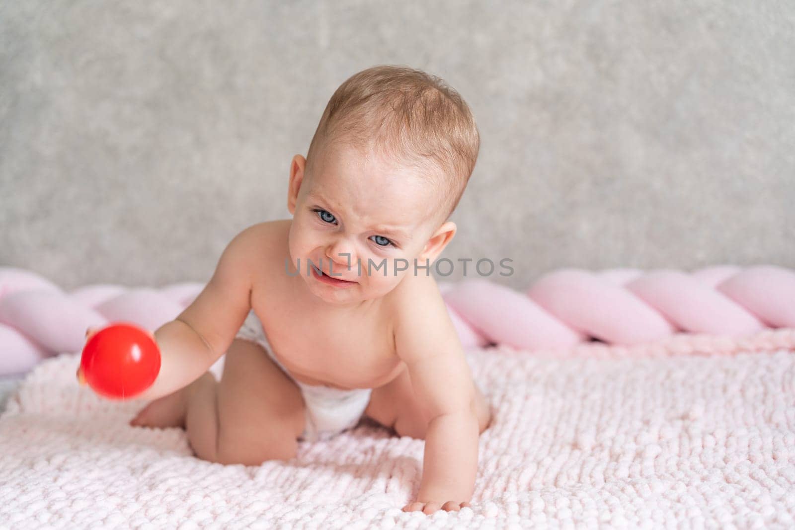 A child is crying holding a ball in his hand.