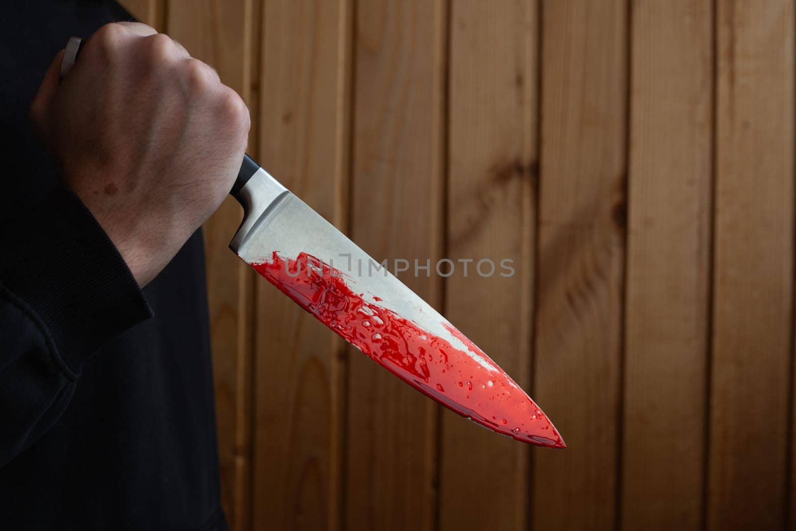 Bloody knife in hand with reverse grip, criminal holding murder weapon