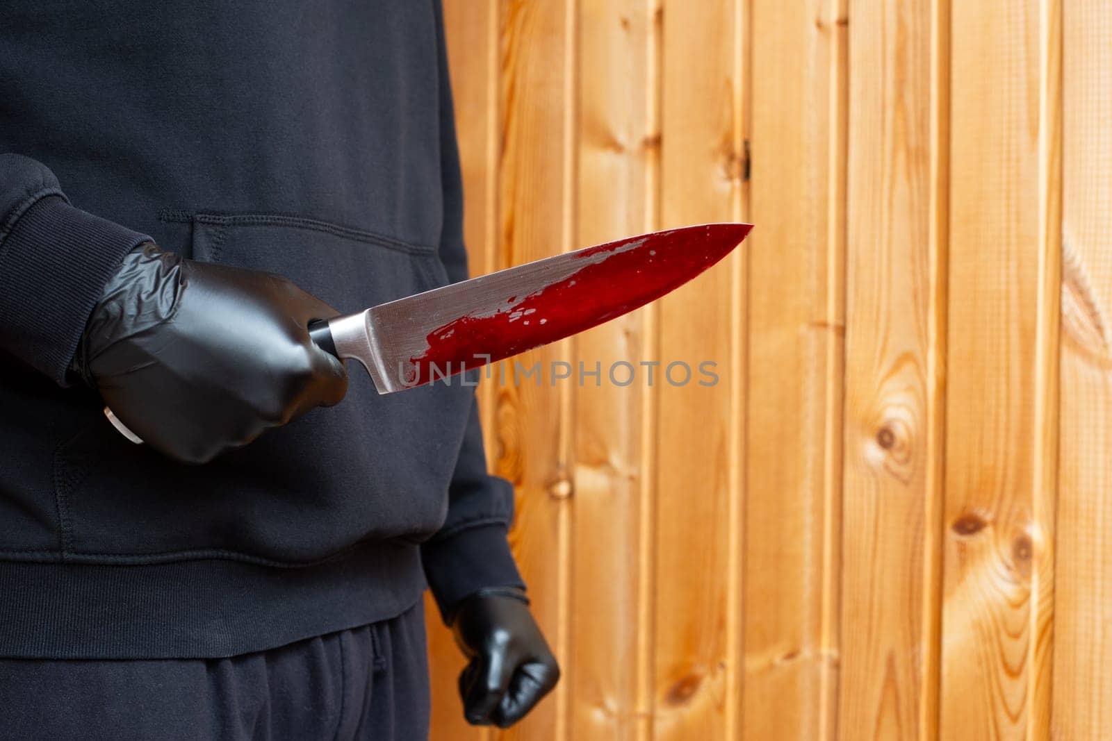 Criminal holds bloody knife in his hand, killer in black gloves with knife with dripping blood