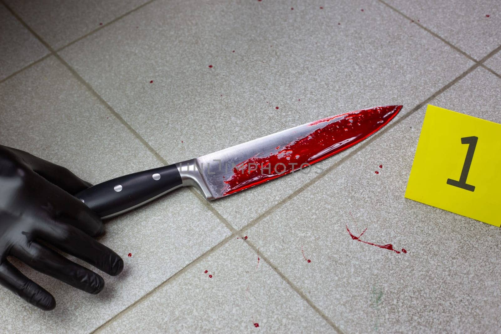 Hand of criminologist takes bloody knife at crime scene, collecting evidence on the floor after crime