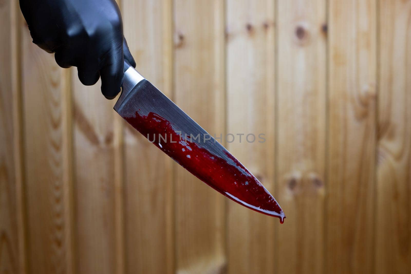 Killer holds bloody knife in his hand, drops of blood flowing down on the murder weapon in the hand of maniac