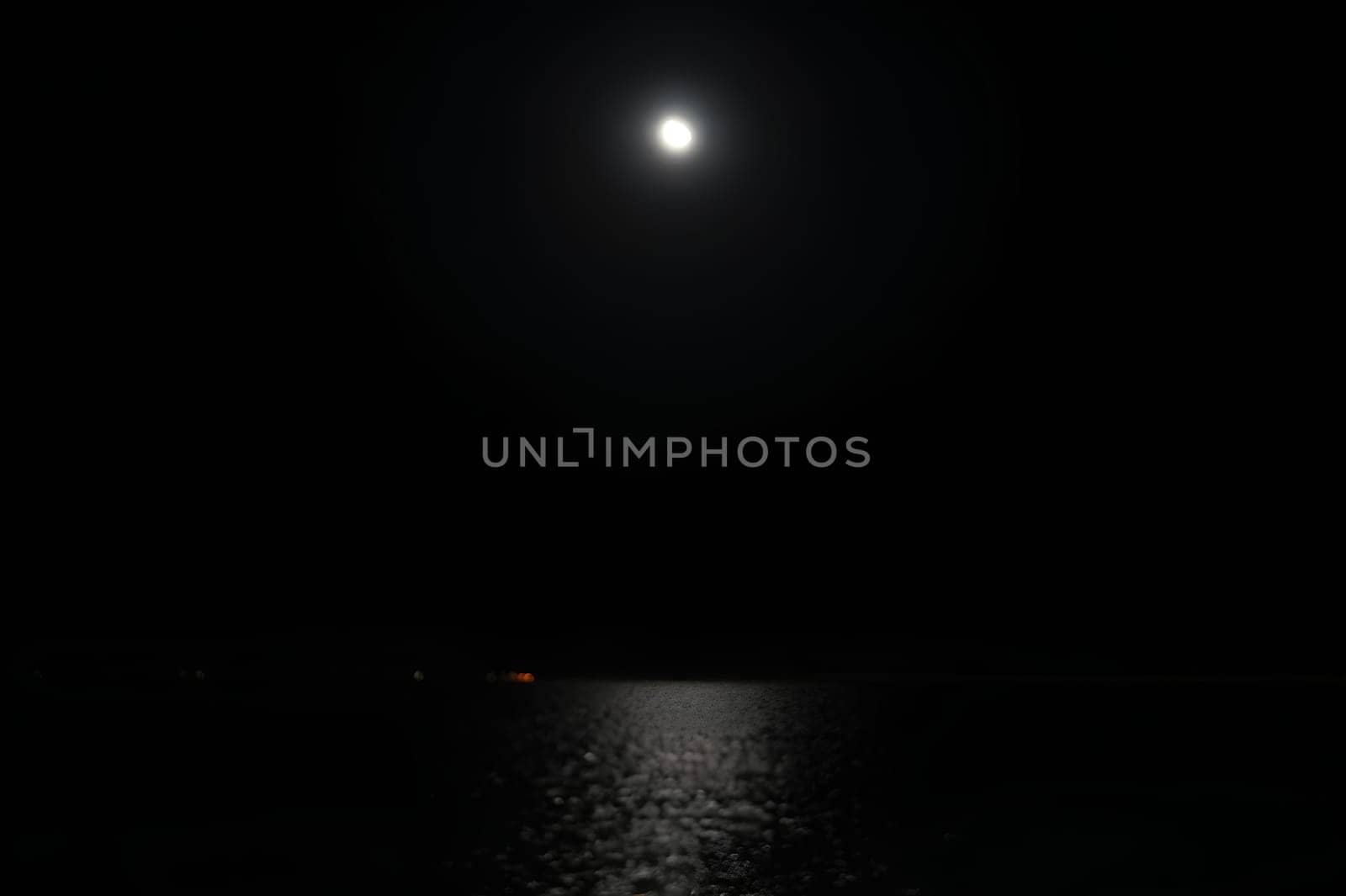 A dark night sky with a full moon and water