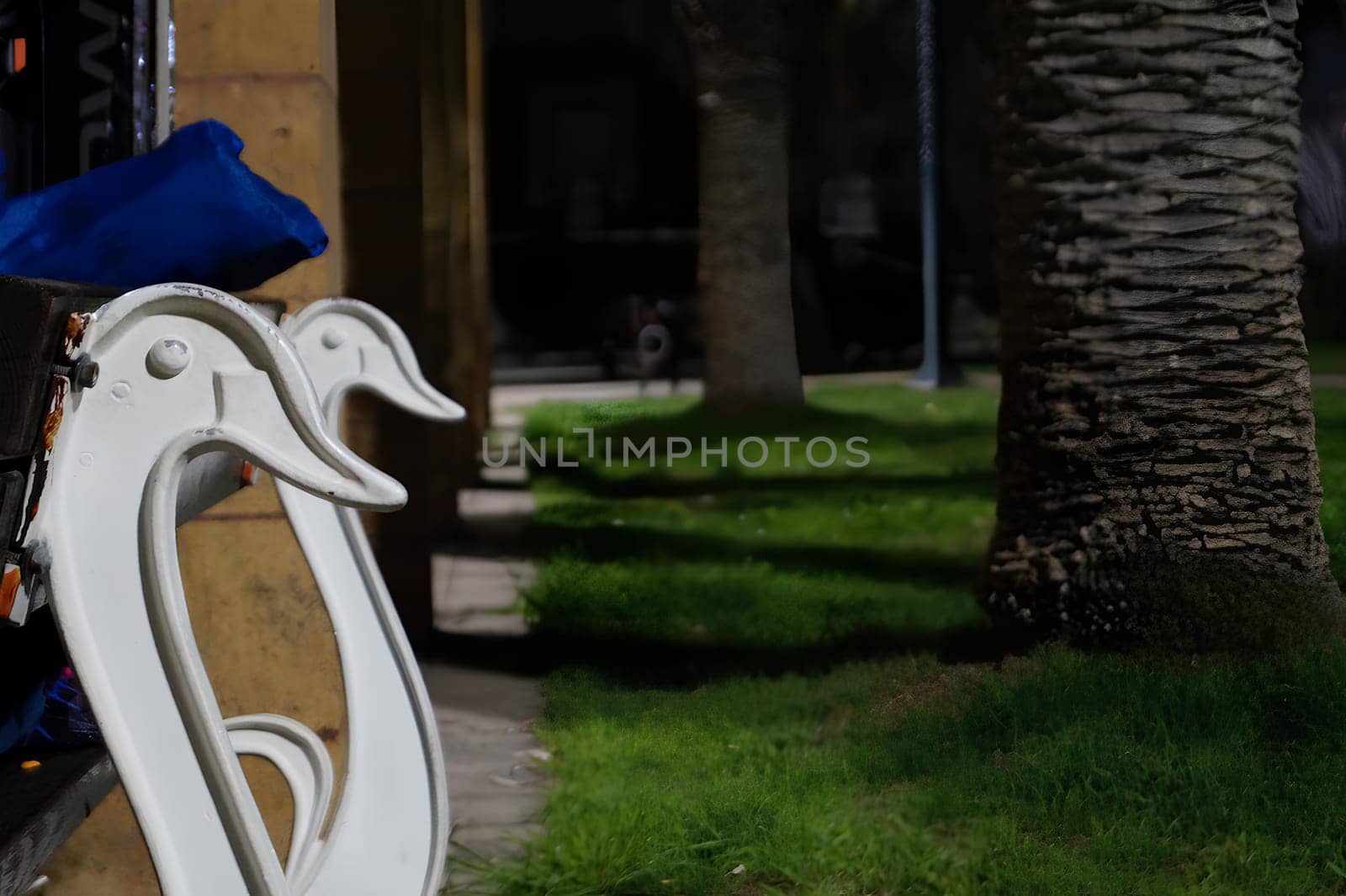 A bench with two white swans on it is in a park