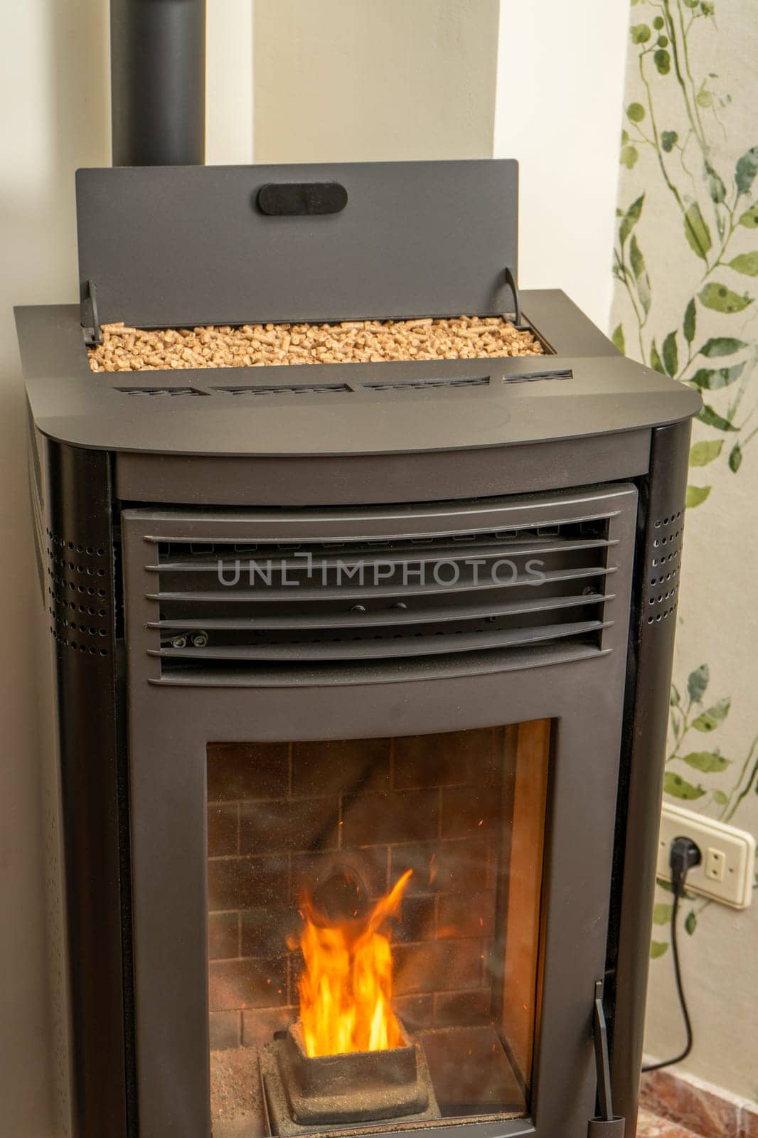 Vertical image of a modern pellet stove with the hopper full to overflowing, ecological and sustainable heat, renewable energy by Barriolo82