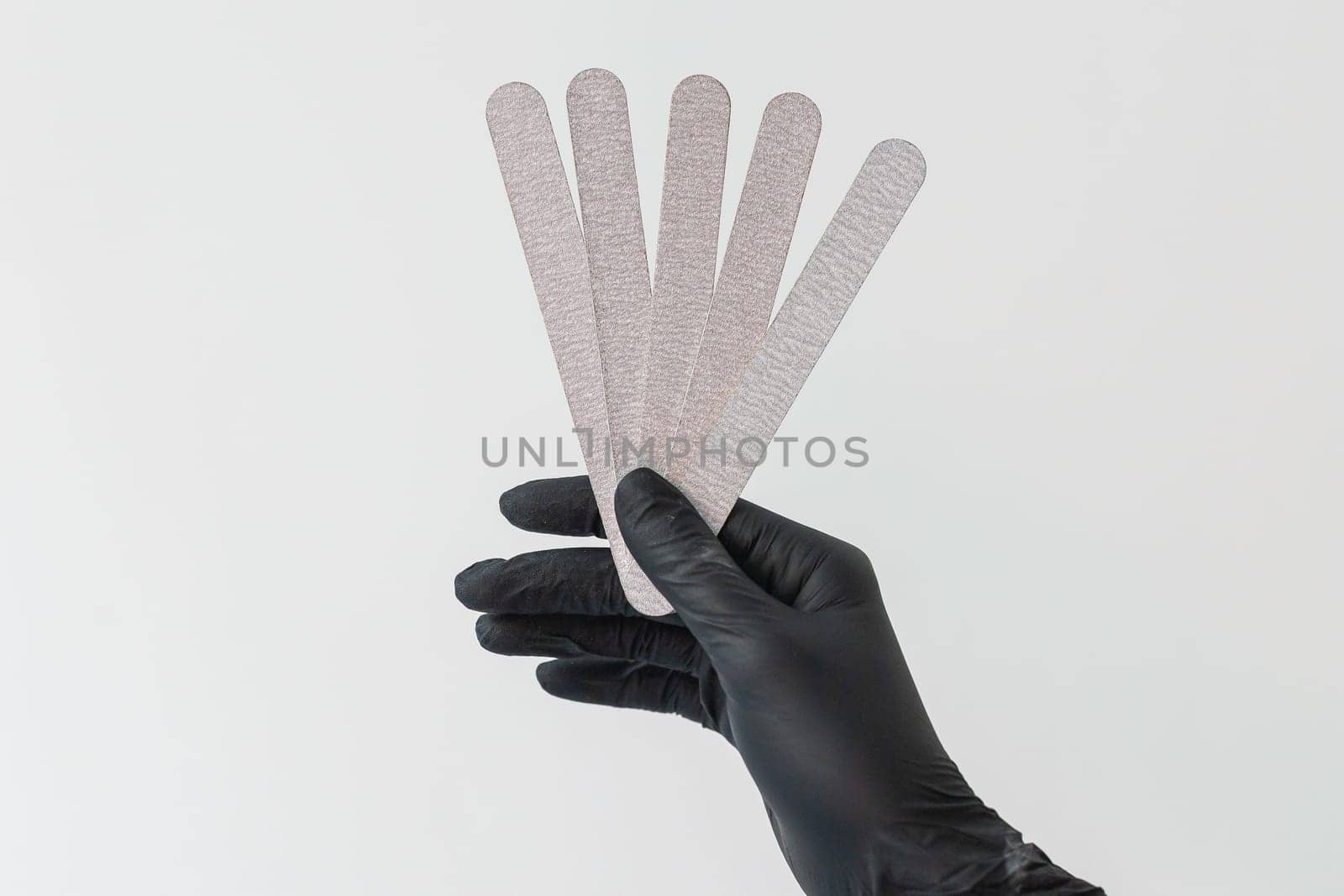 Female hand holds nails files on white background. Concept of polishing nails. Spa treatment beauty. White background with copy space