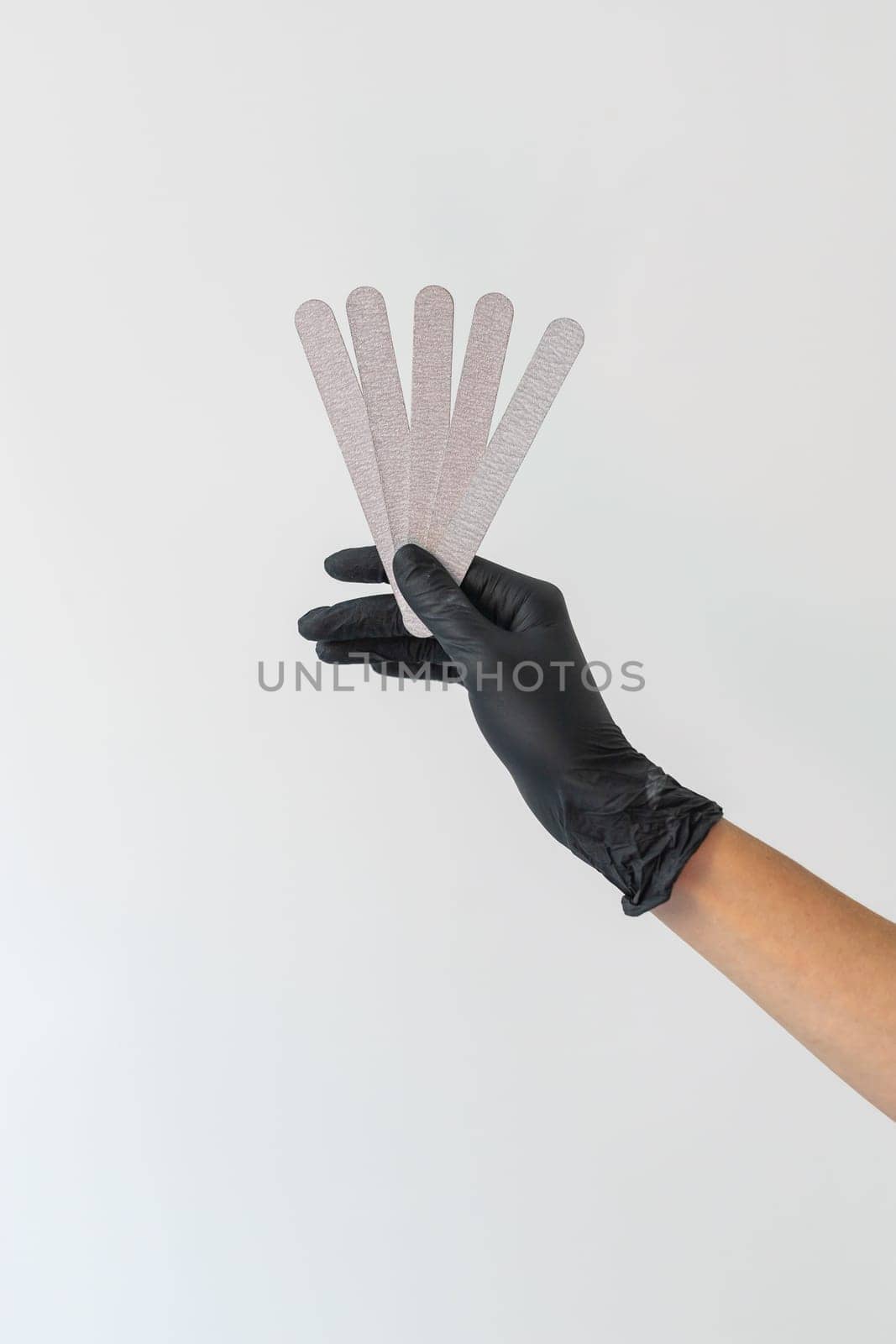 Female hand holds nails files on white background. Concept of polishing nails. Spa treatment beauty. White background with copy space. by Satura86
