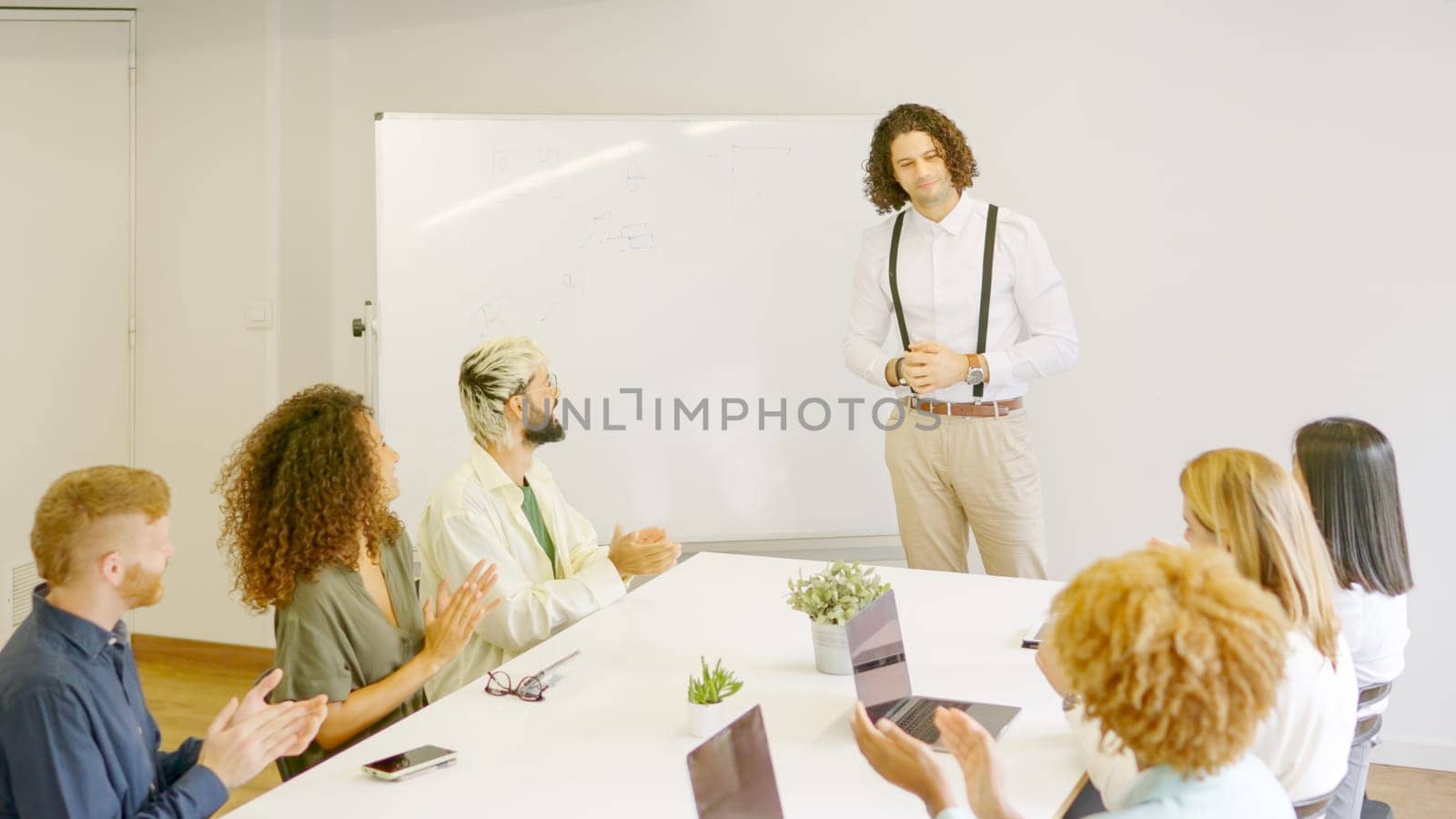 Team applauding a man after a presentation in a meeting room