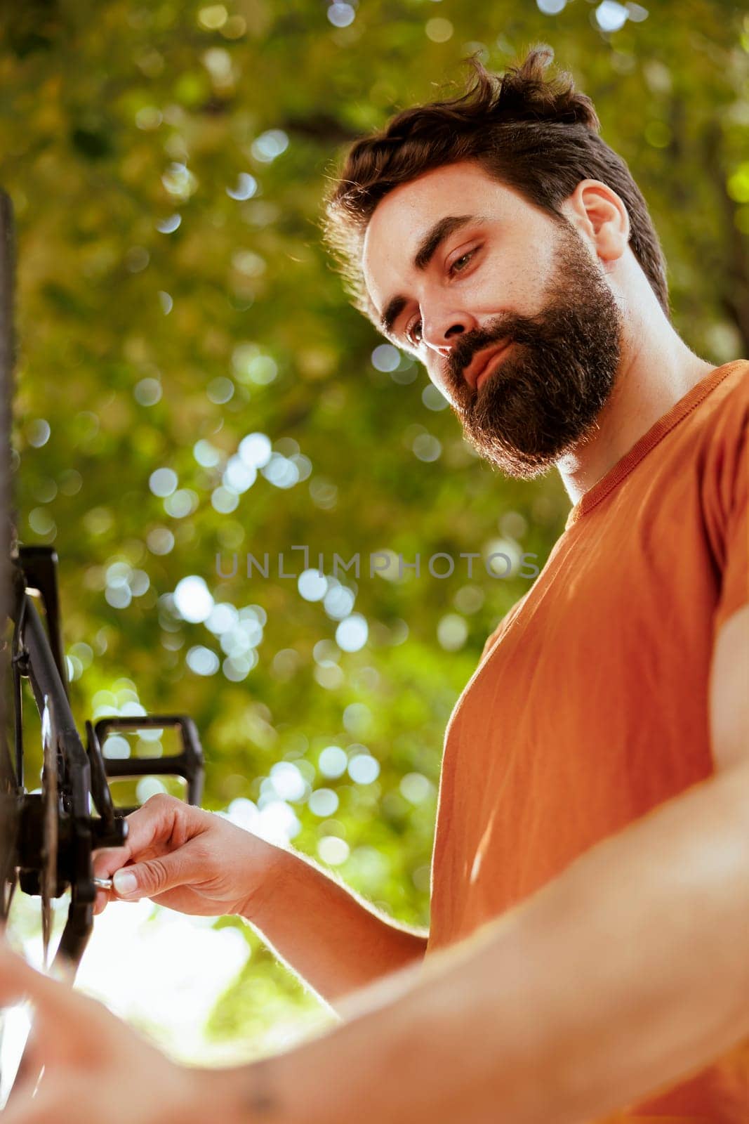Man securing bicycle parts outdoors by DCStudio