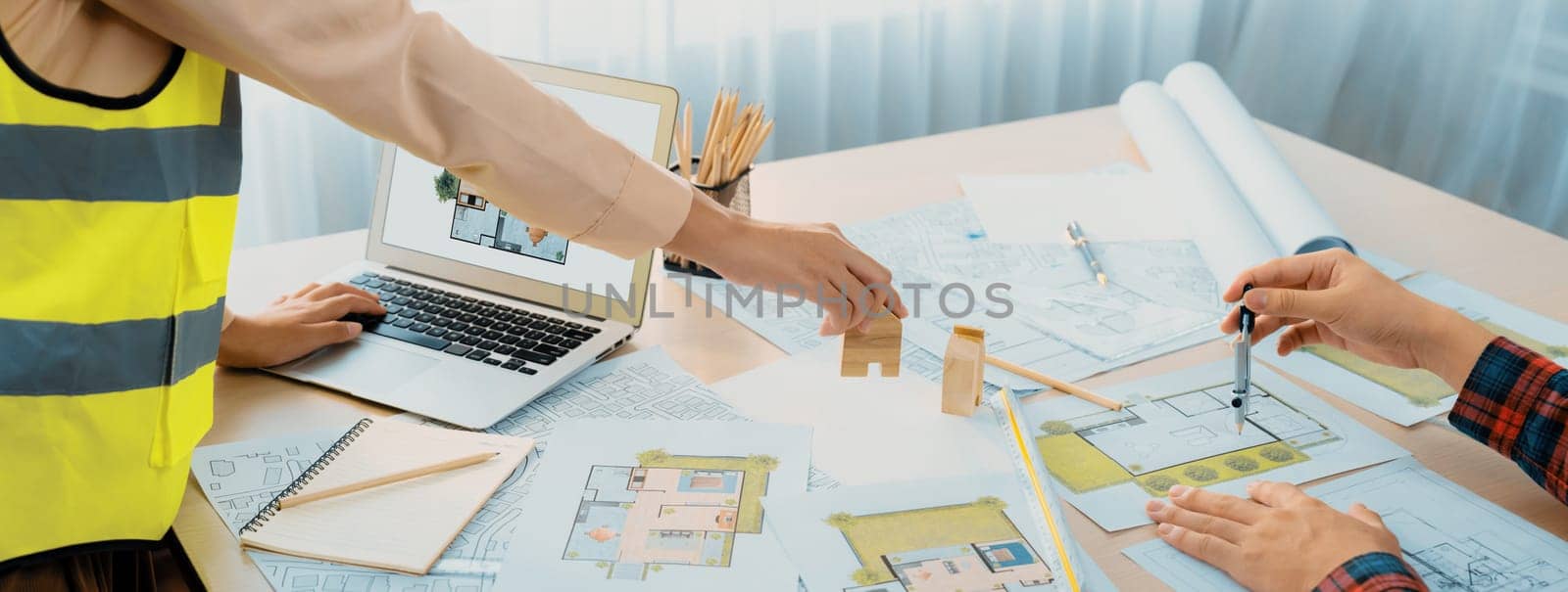 Professional engineer and architect collaborate on eco house project at meeting table with green design blueprint and architectural equipment at modern office. Focus on hand. Close up. Delineation.