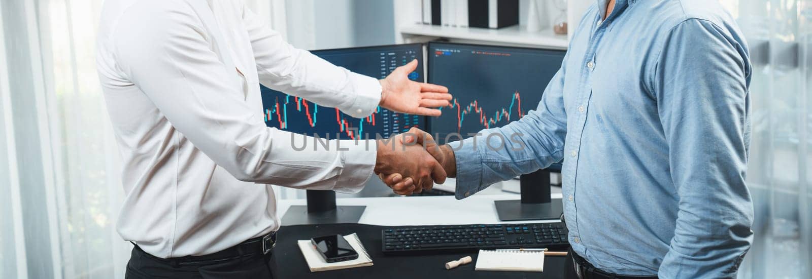 Businessman in stock traders checking hands for successful high profit investment on panorama view. Concept of dealing with each others in technology market on dynamic graph background. Sellable.