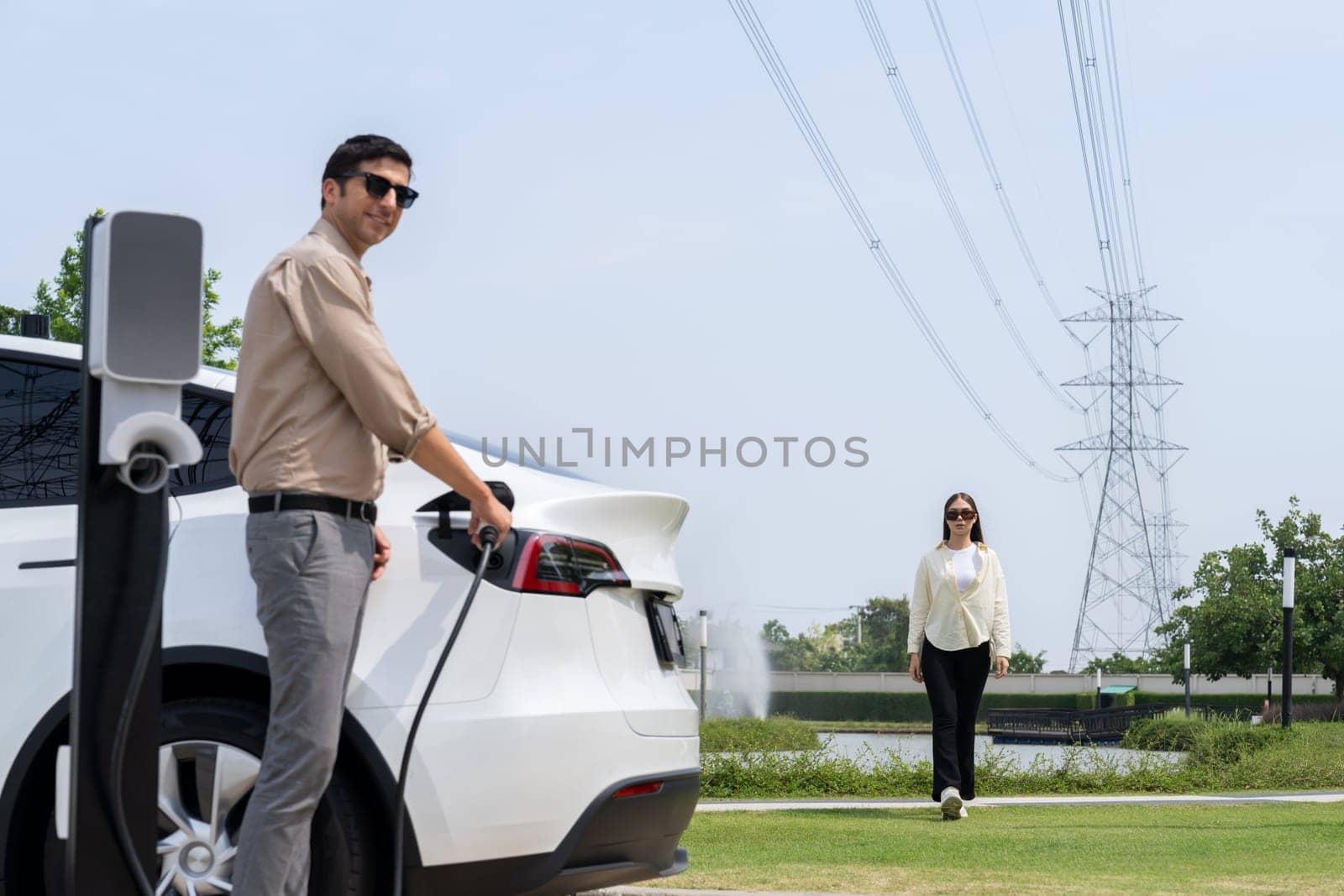 Young couple recharge EV car battery at charging station. Expedient by biancoblue