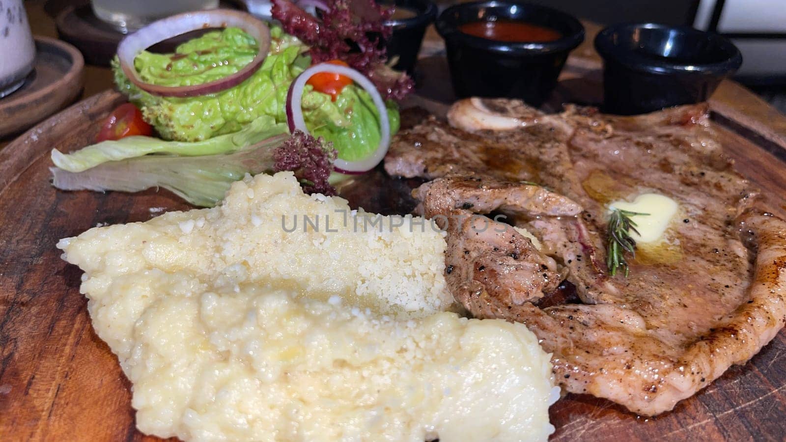 Juicy beef steak with salad and mashed potato along with pepper corn sauce served on wooden plate wooden stone table. Top view on a restaurant
