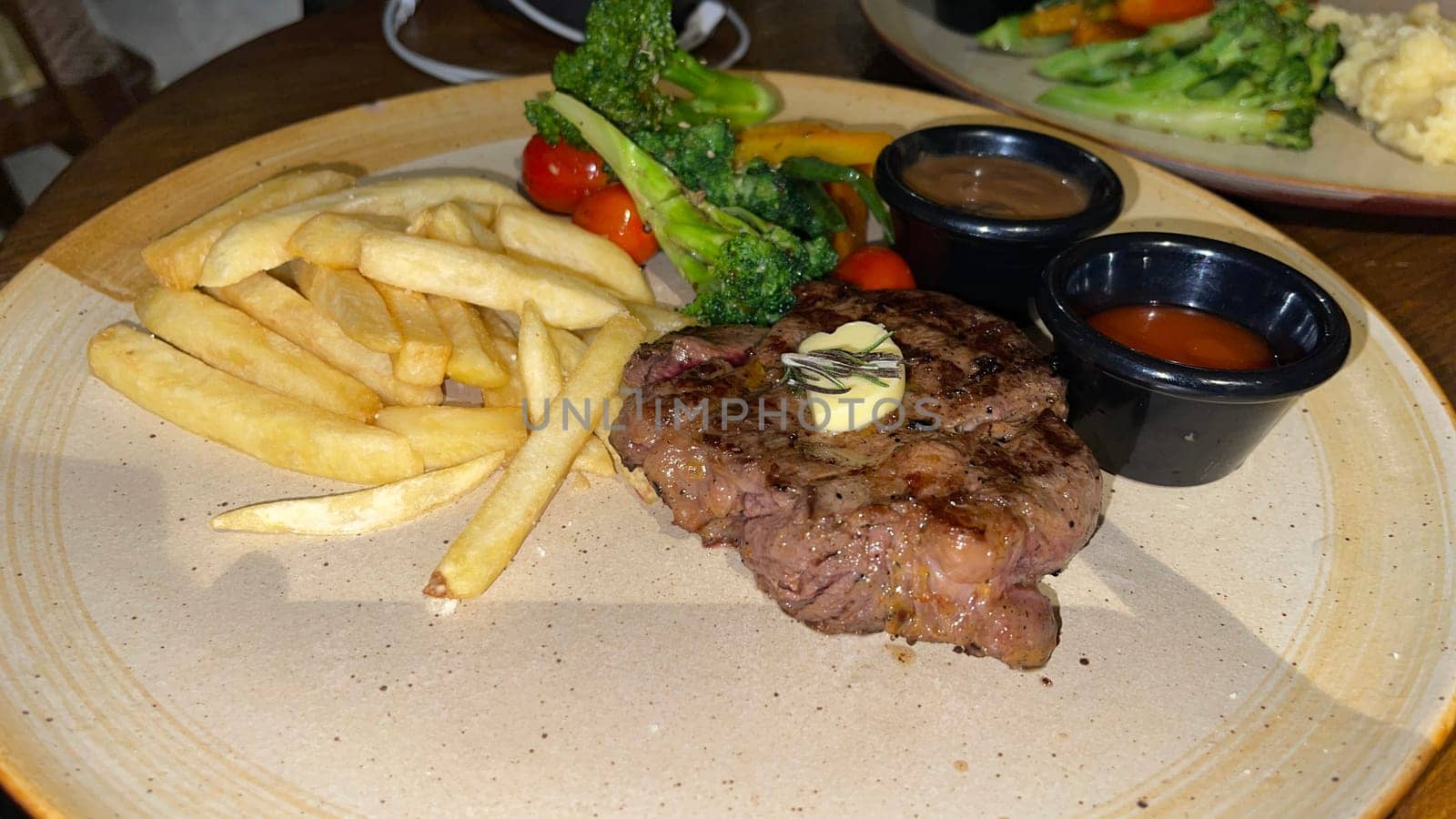 Juicy beef steak with salad and mashed potato along with pepper corn sauce served on wooden plate wooden stone table. Top view on a restaurant