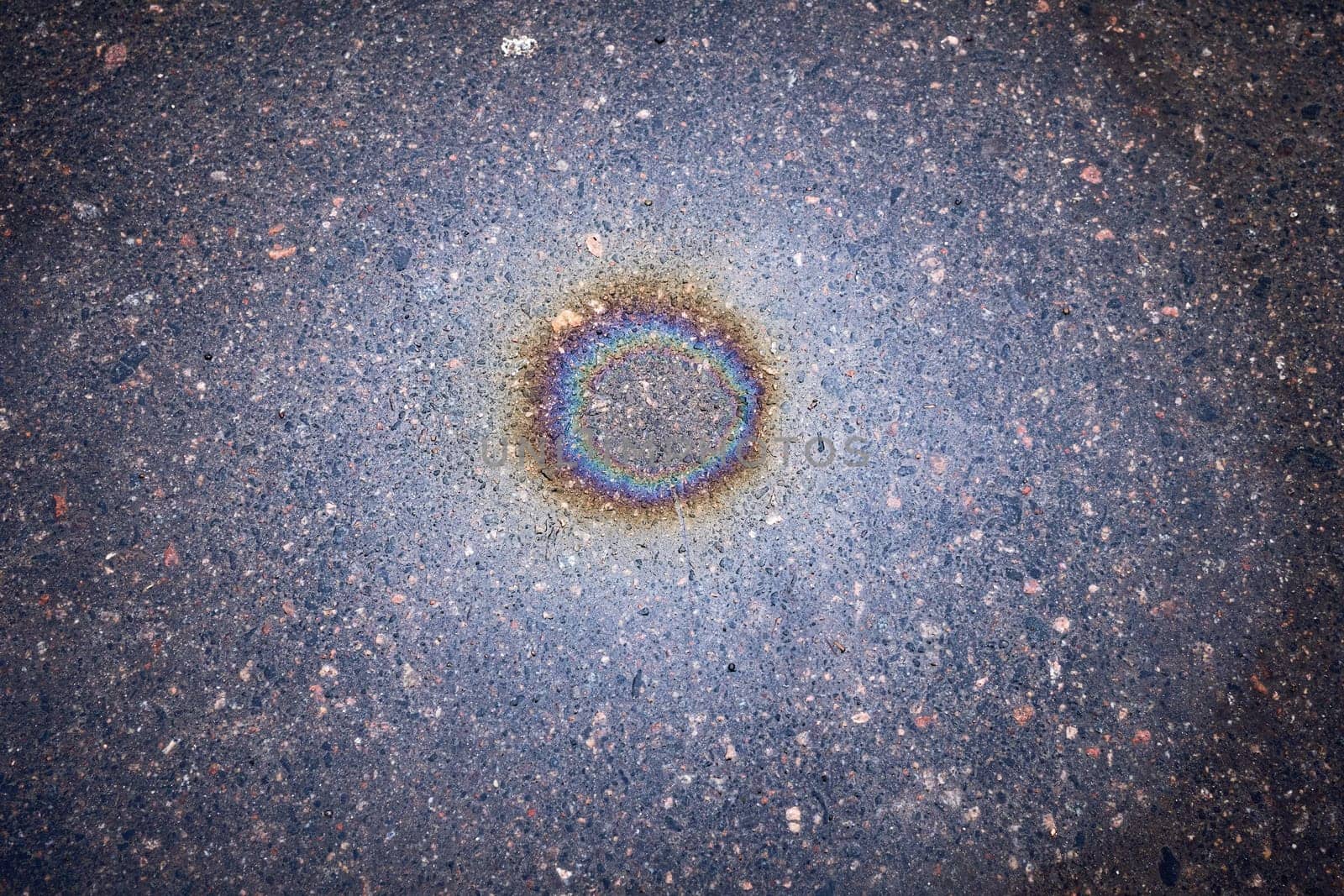 Oil spill on asphalt in the form of a stain. Abstract background from motor oil, gas or petrol spilled on asphalt