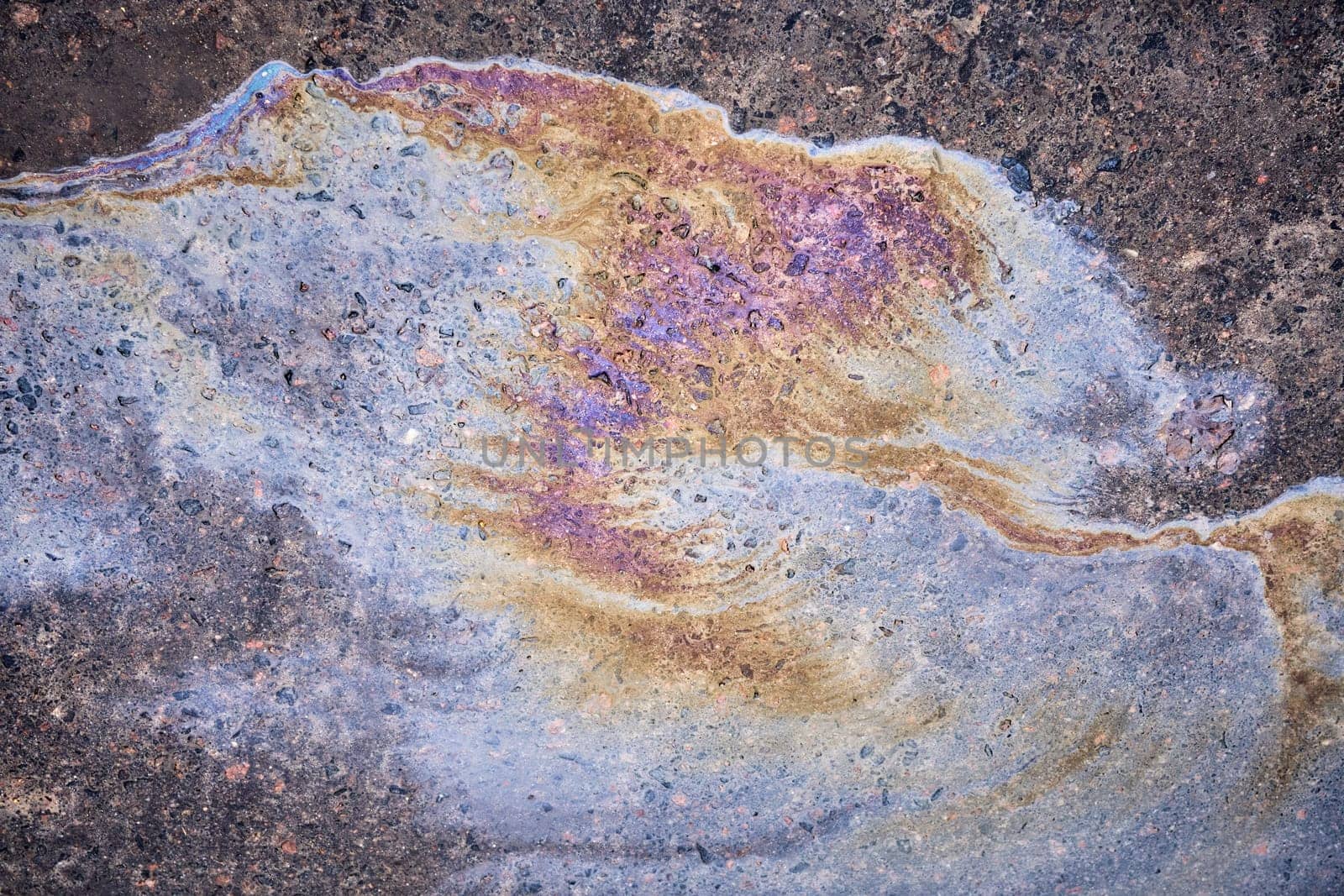 Textured stain of fuel or oil on wet asphalt on a rainy day. The concept of environmental pollution.