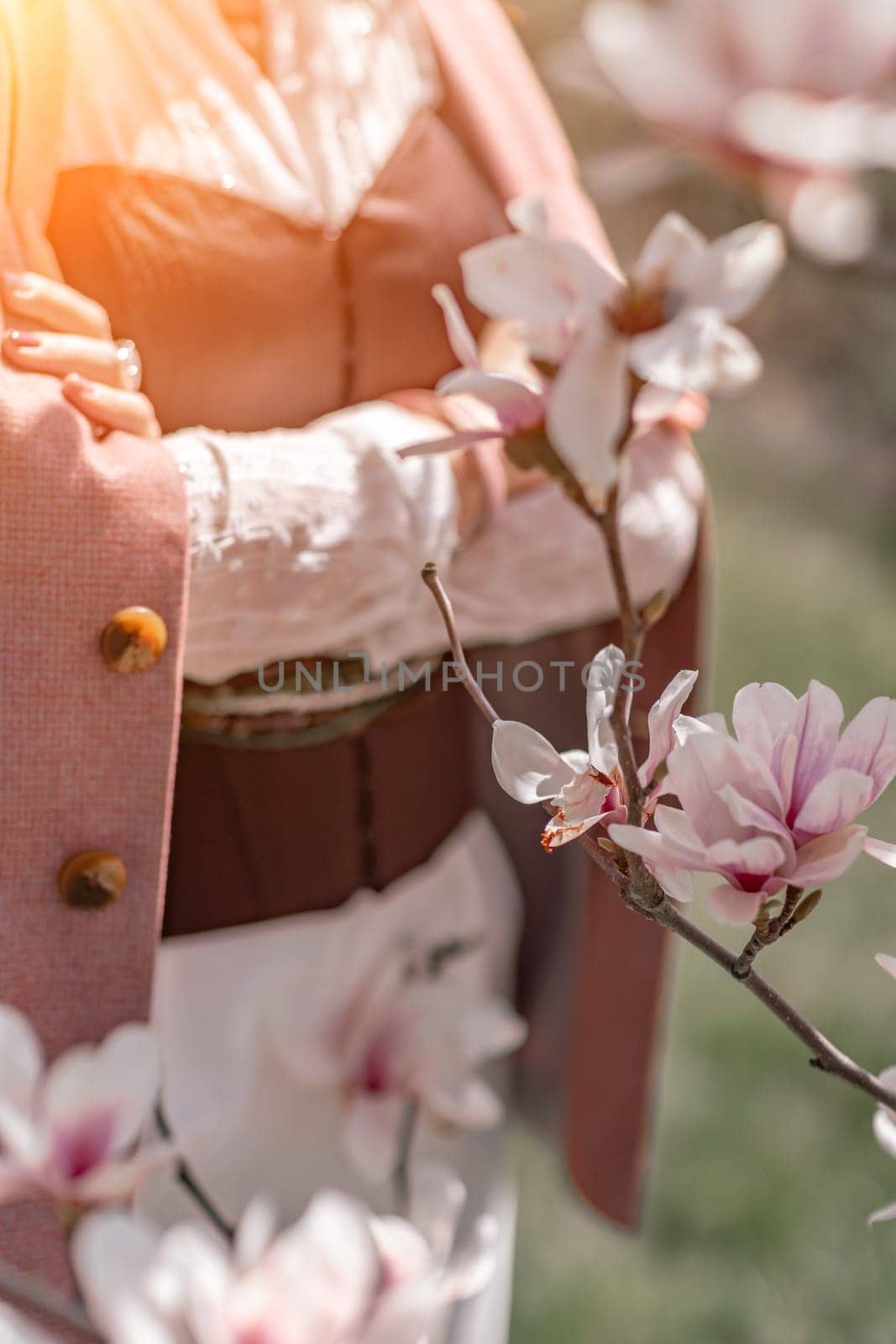 Magnolia park woman. Stylish woman stands near the magnolia bush in the park. Dressed in white corset pants and posing for the camera. by Matiunina