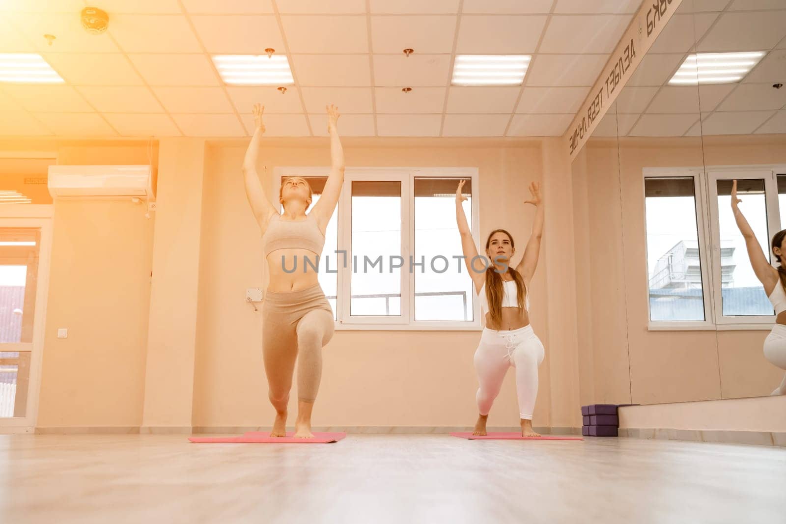 Two beautiful women do yoga, sports in the gym. The concept of grace and beauty of the body