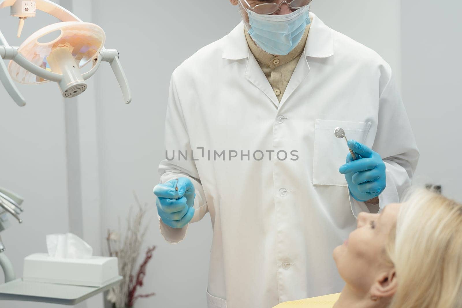 Dental doctor treating a female patient in hospital. by Сookiestock