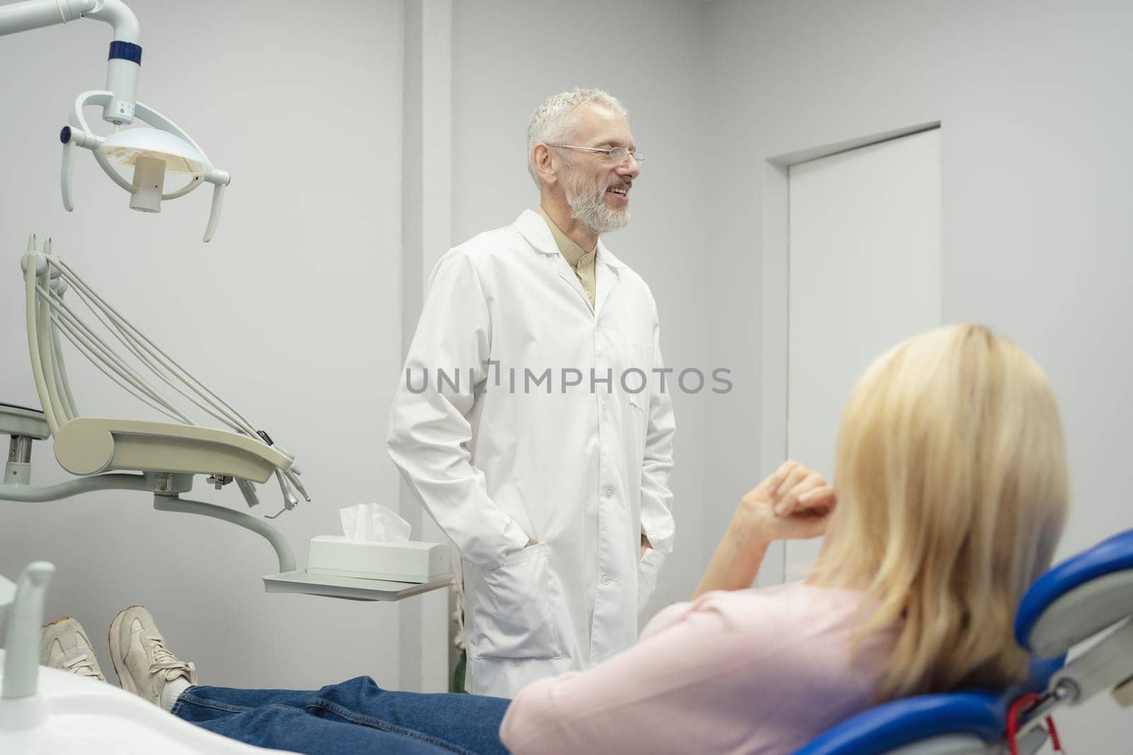 Dental doctor treating a female patient in hospital. by Сookiestock