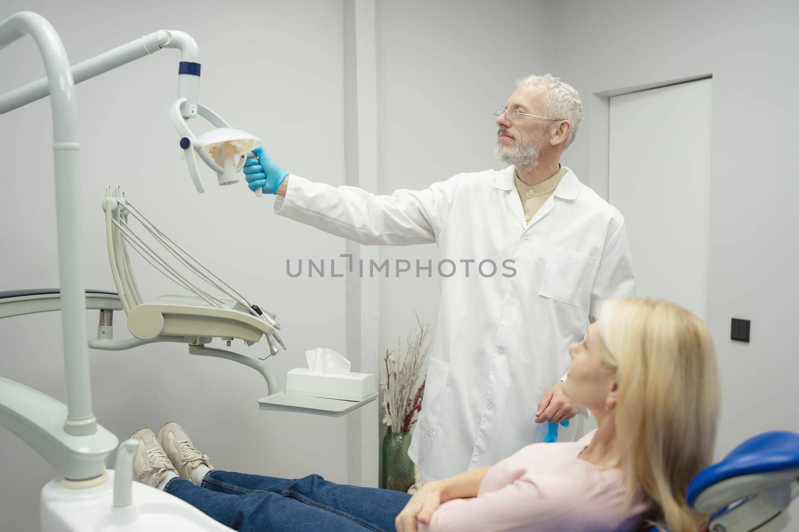 Dental doctor treating a female patient in hospital. by Сookiestock