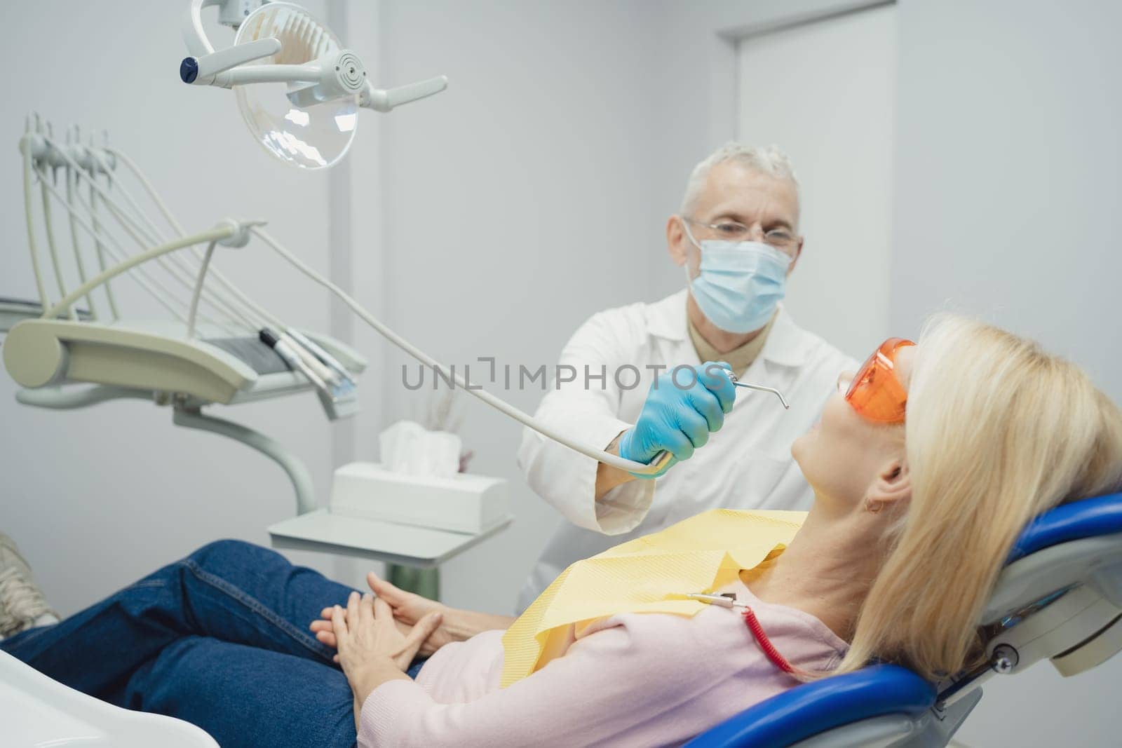 Dental doctor treating a female patient in hospital. by Сookiestock