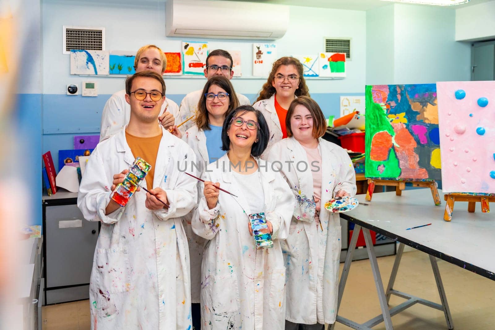 Portrait of a class painting group with white coats with mental disabled people